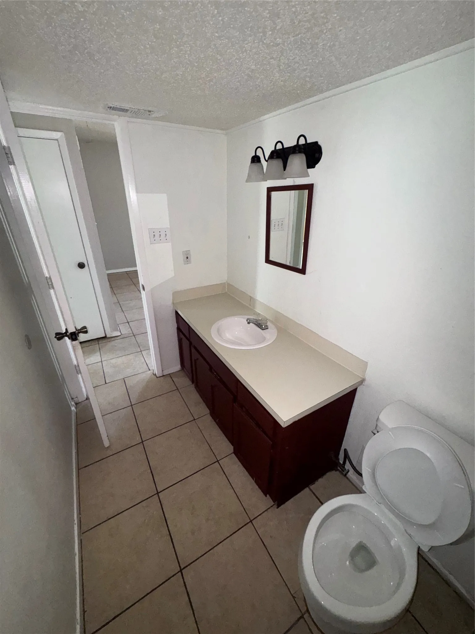 Bathroom featuring a dark wood-finish vanity with an integrated sink, light-toned countertop, and tile flooring