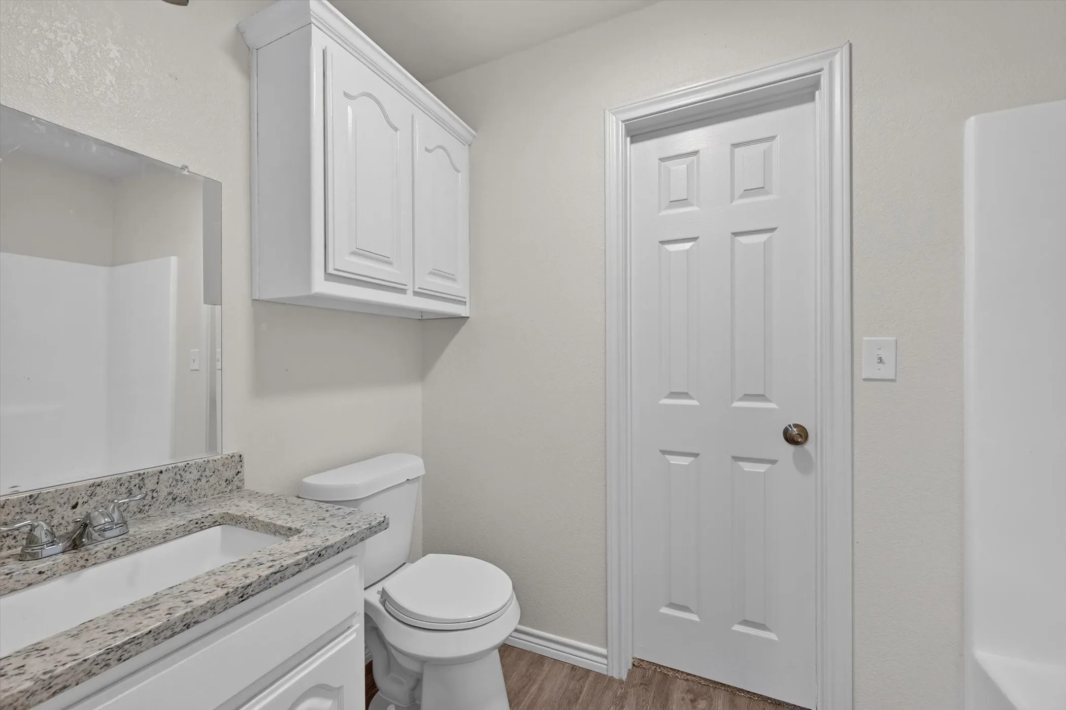 Bathroom featuring a white vanity with a speckled countertop, a rectangular undermount sink, and a chrome faucet