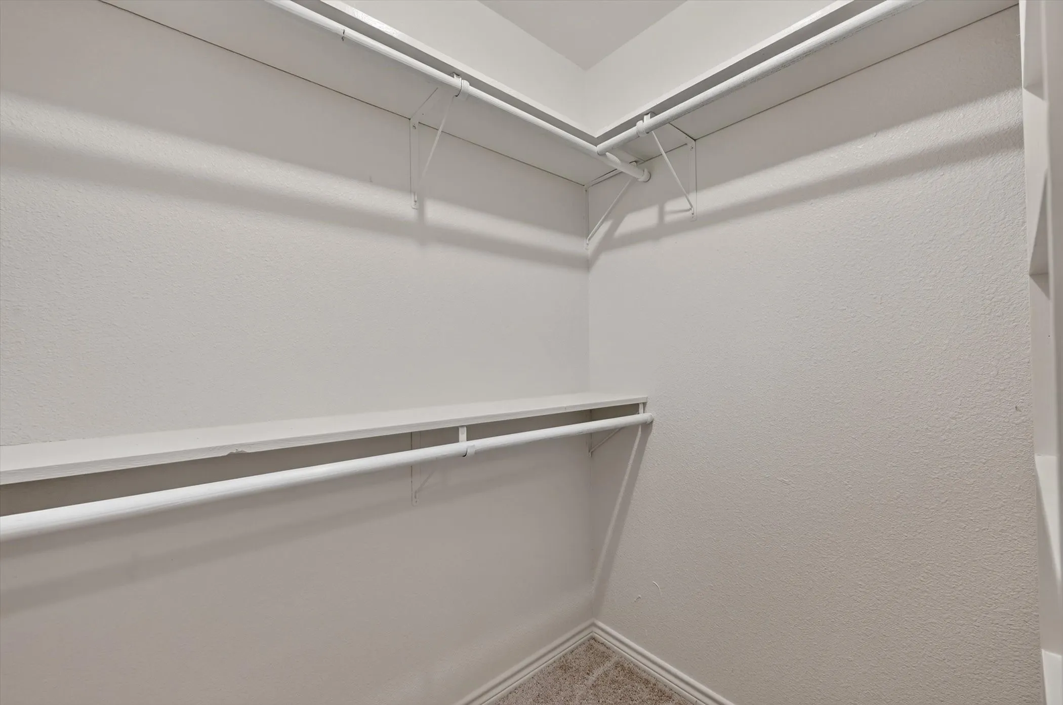 Walk-in closet with white shelving and hanging rods