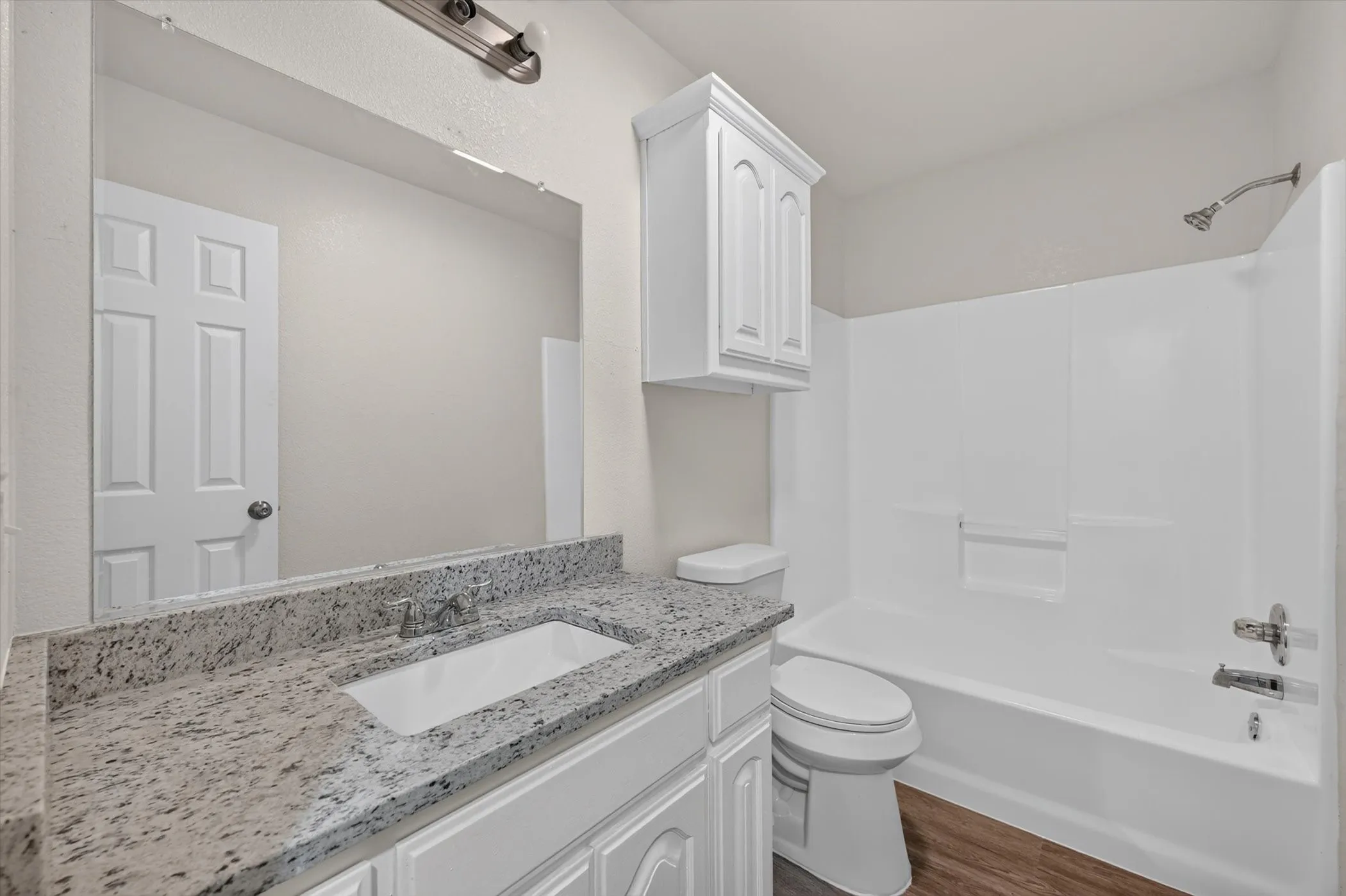 Bathroom featuring a white vanity with paneled doors, light granite-style countertop, and an integrated rectangular sink