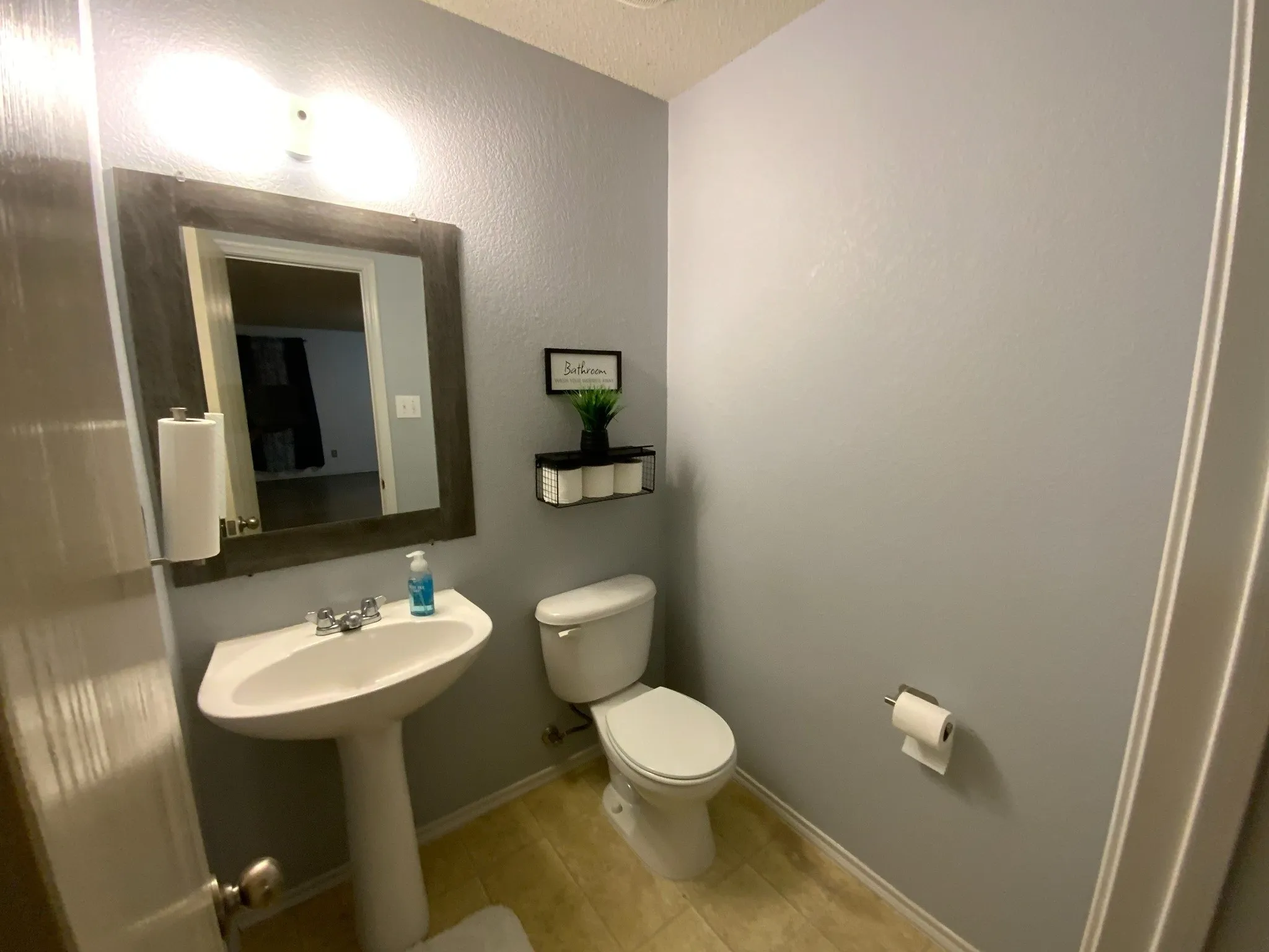 HALF BATH on the 1st Floor: Pedestal sink with chrome fixtures, framed mirror, and light gray wall paint