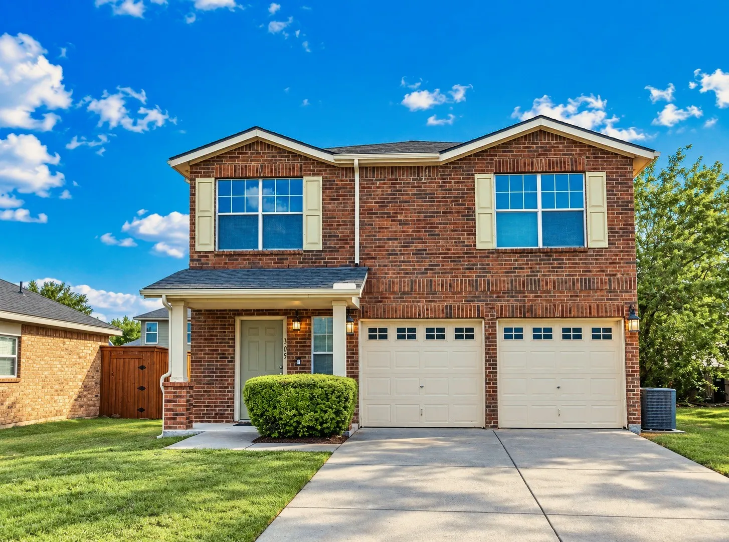 Brick exterior with gabled roof lines, covered front entry, two-car garage, and concrete driveway