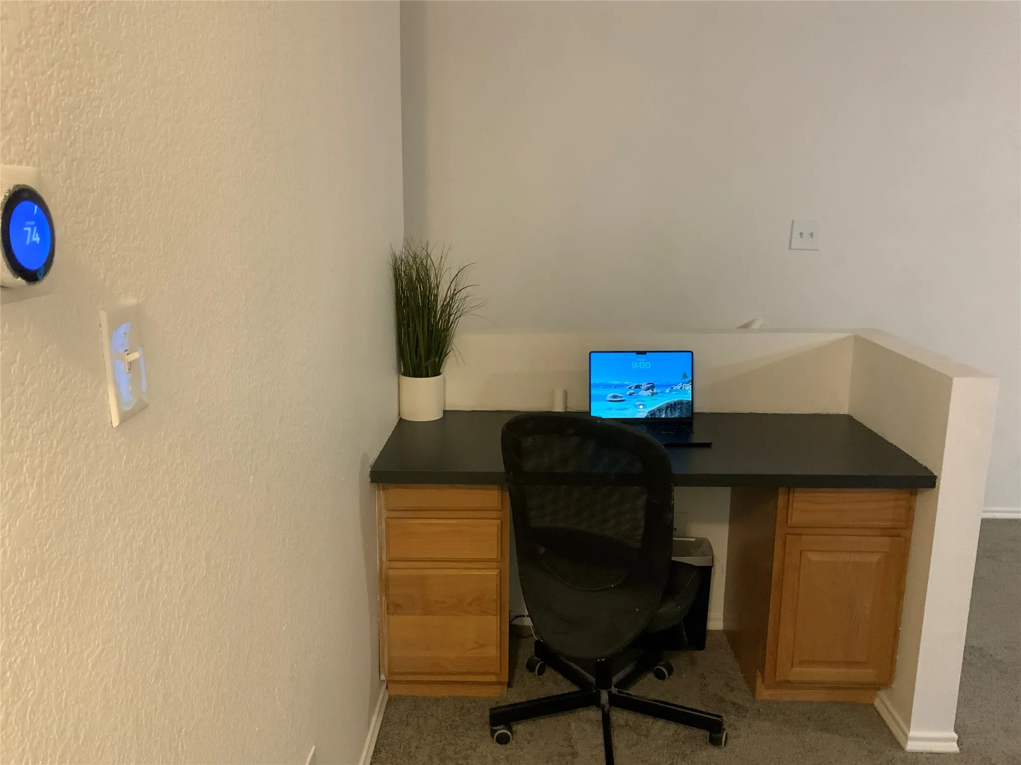 Built-in desk featuring a dark countertop and light wood-finish cabinetry