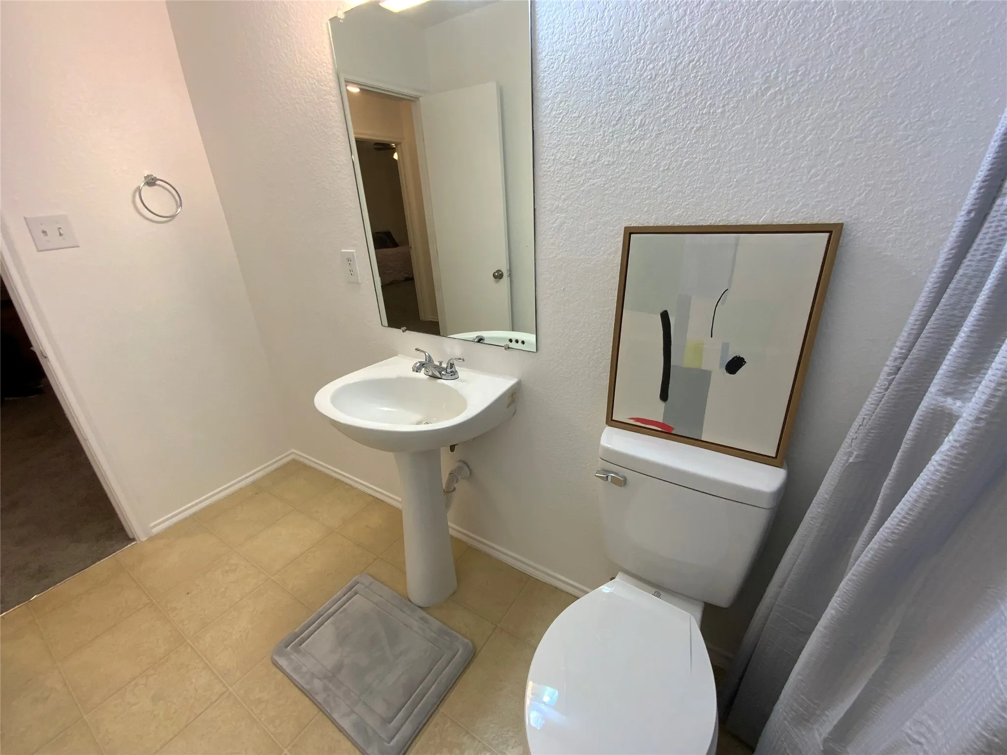 Bathroom featuring a pedestal sink, wall-mounted mirror, and tile-finish flooring