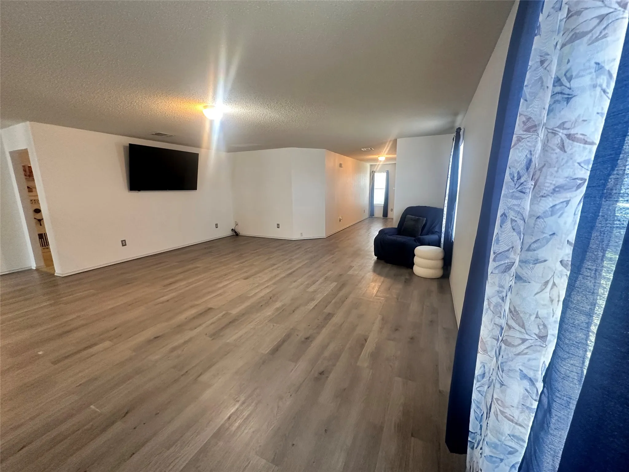 Wood-finish flooring throughout, white walls, and a recessed ceiling light fixture