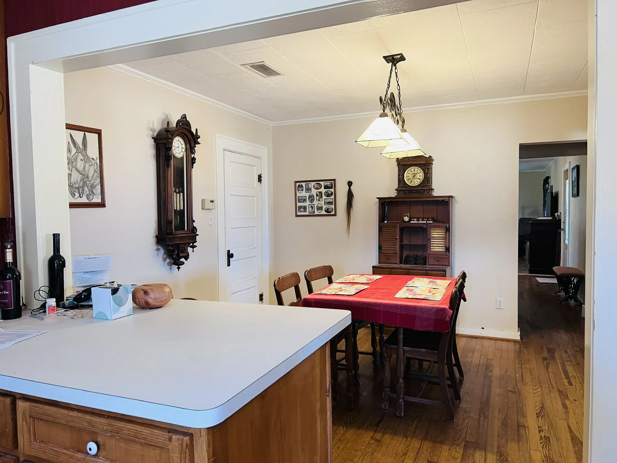 Dining area with wood flooring, a decorative pendant light fixture, and crown molding