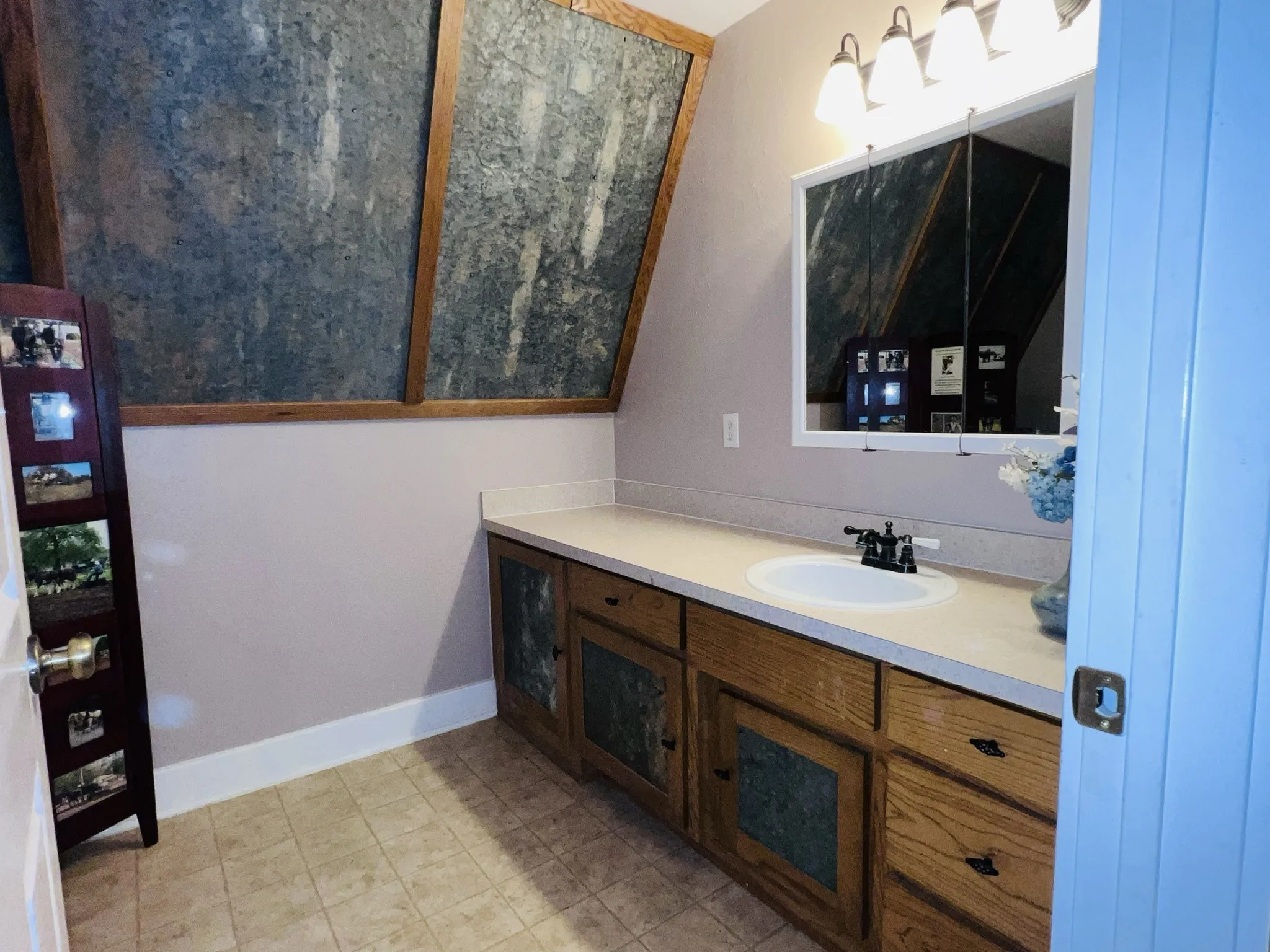 Upstairs full bathroom featuring a light-colored countertop, an undermount sink with a two-handle faucet, and wooden cabinetry with dark hardware
