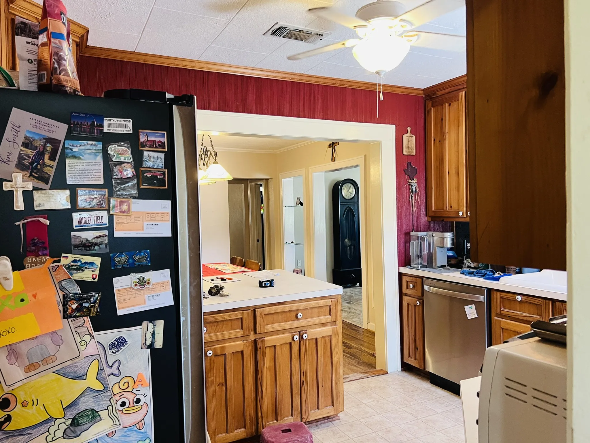 Kitchen featuring wood cabinetry, white countertops, a stainless steel dishwasher, and a ceiling fan with integrated lighting