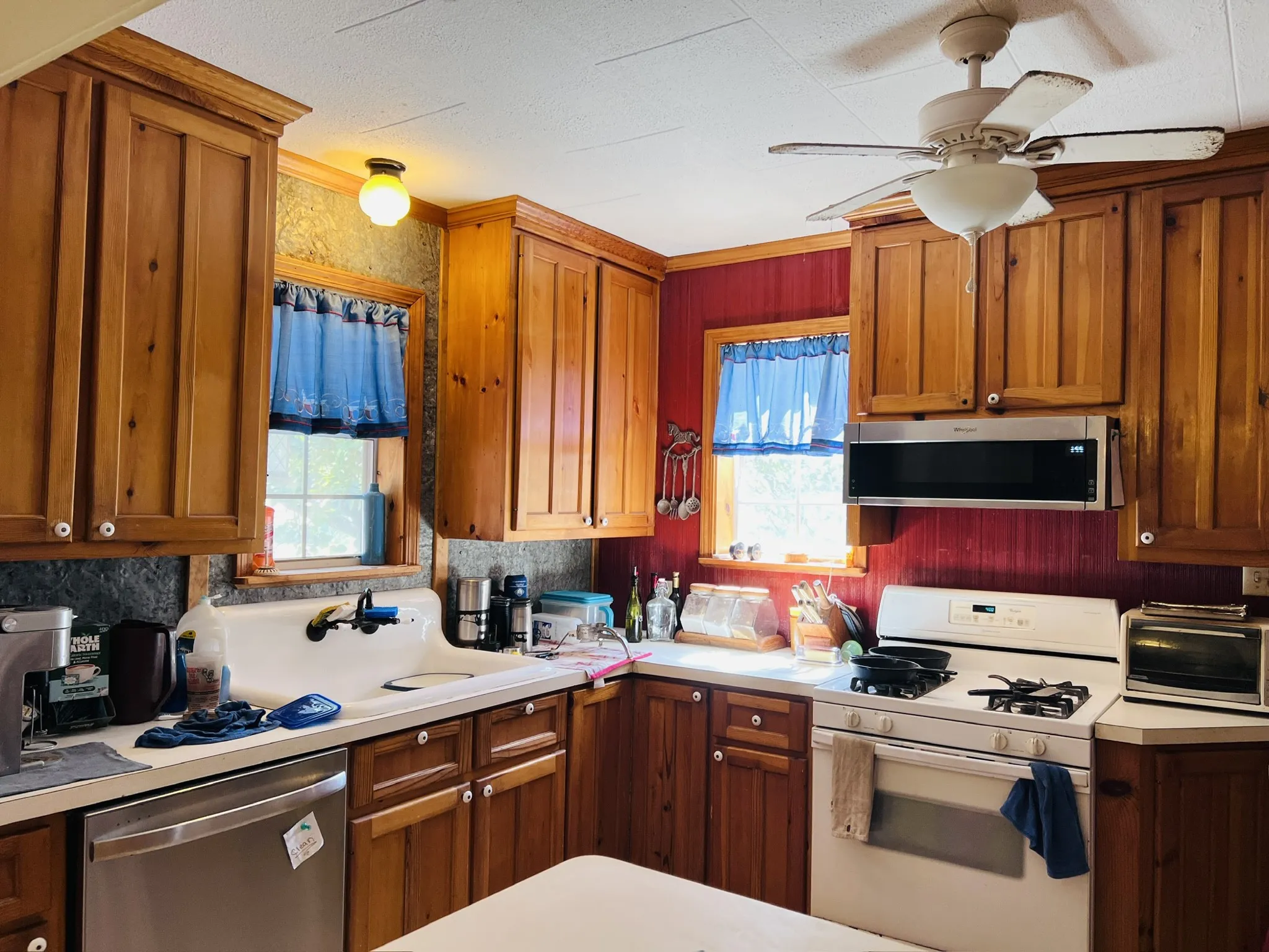Kitchen featuring natural wood cabinetry, a white gas range, a stainless steel over-the-range microwave, and a white sink