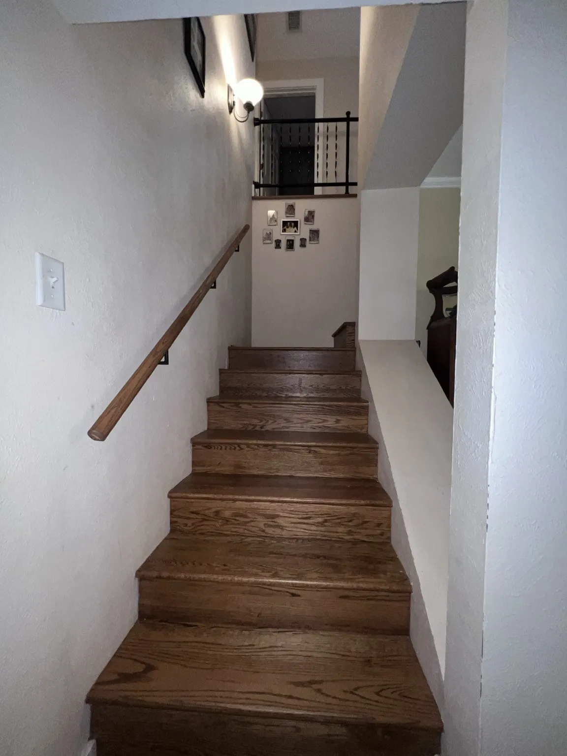 Hardwood staircase featuring a wood handrail and neutral wall finishes