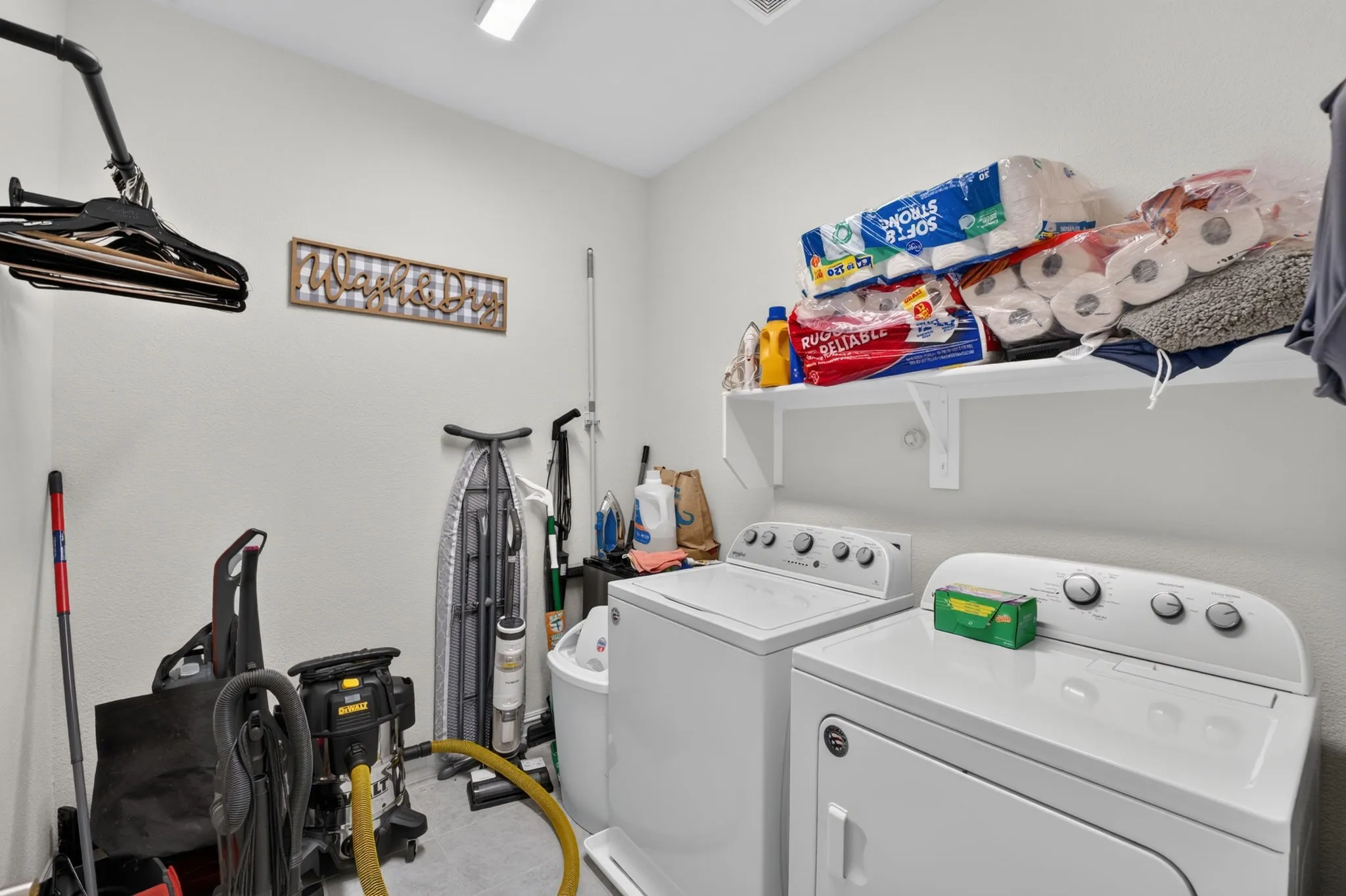 Dedicated laundry area featuring a built-in shelf, overhead lighting, and neutral wall finishes