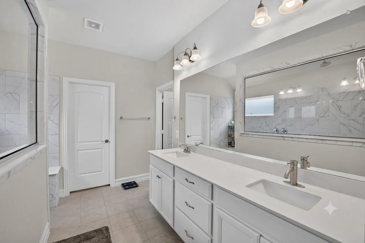 Dual vanity featuring white cabinetry, integrated sinks, brushed nickel fixtures, and a spacious countertop