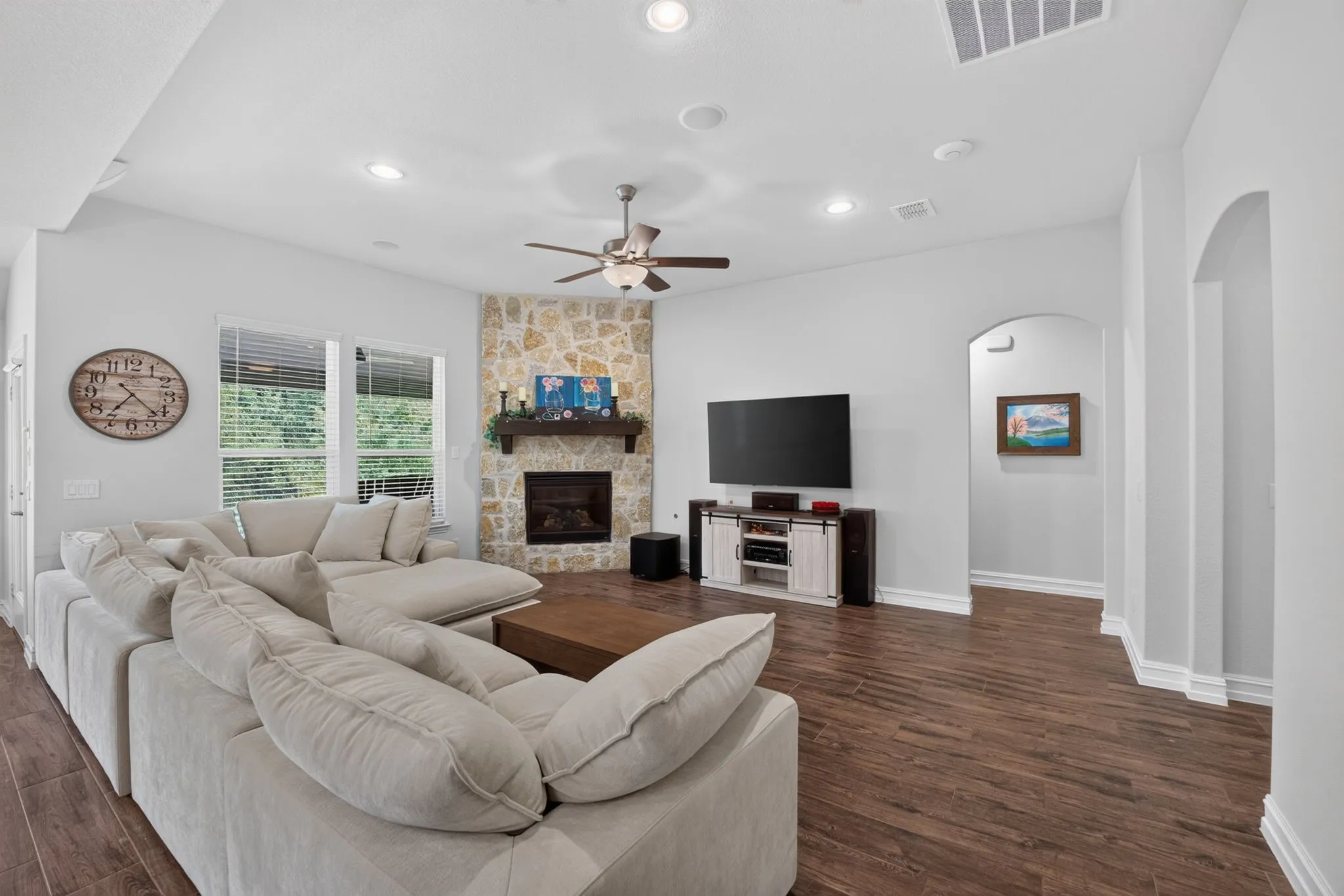 Spacious living room featuring wood-finish flooring and a stone-clad fireplace with a wood mantel