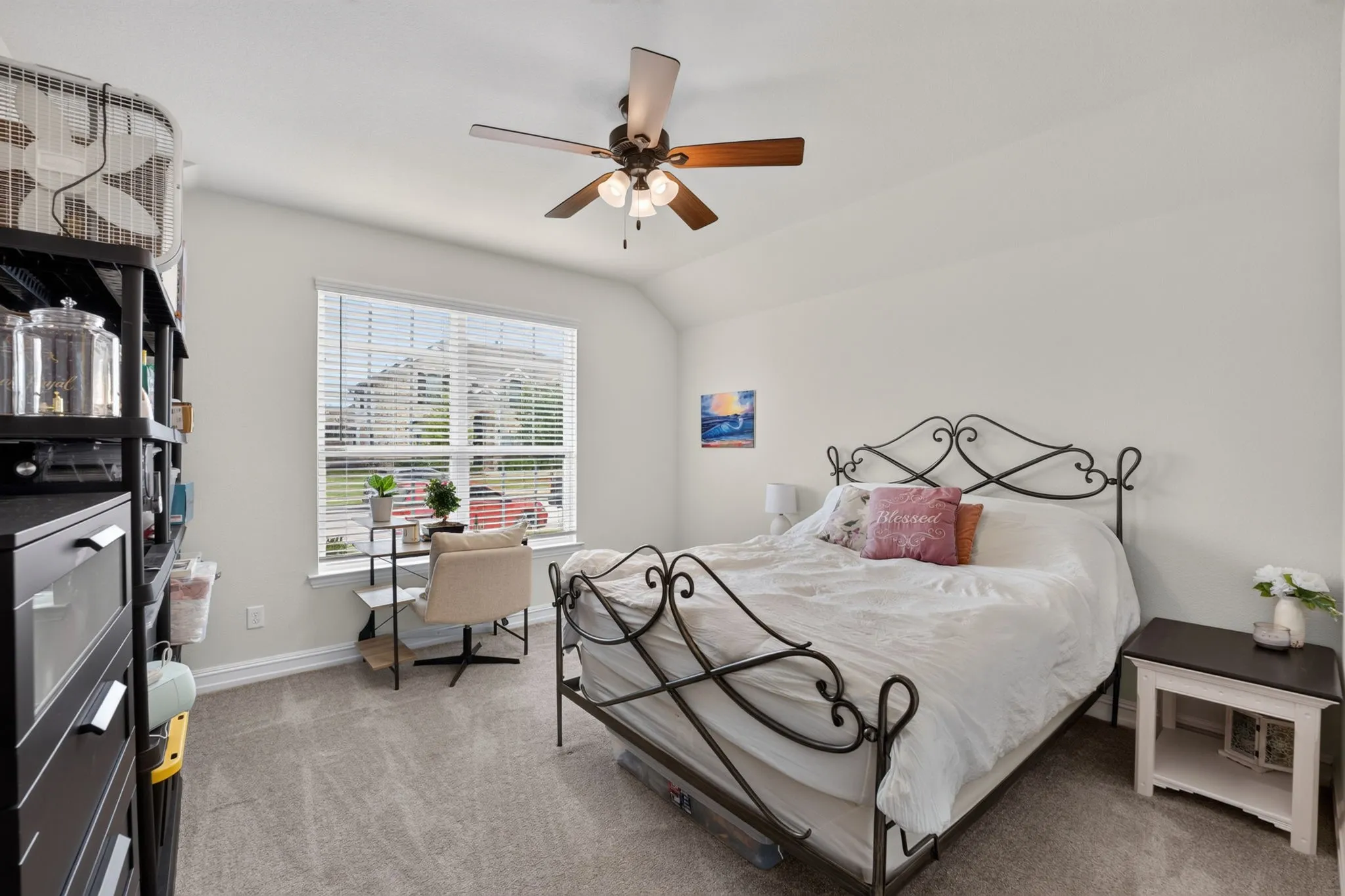 Carpeted bedroom featuring a large window with blinds, a ceiling fan, and light neutral wall colors