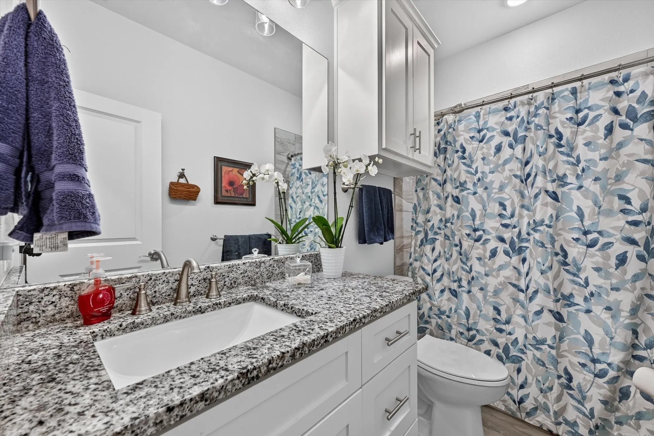 Bathroom featuring a white vanity with a granite countertop, undermount sink, and brushed nickel fixtures