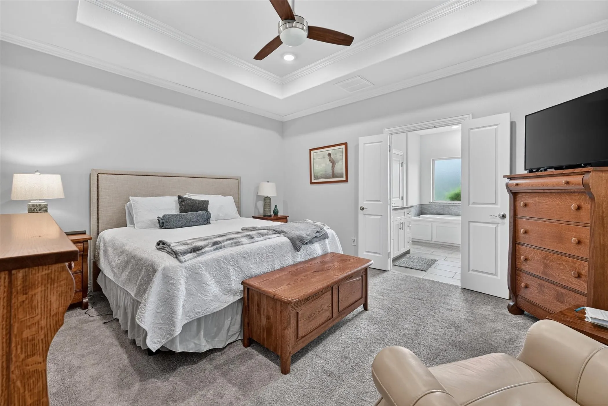 Recessed lighting and a ceiling fan complement the tray ceiling