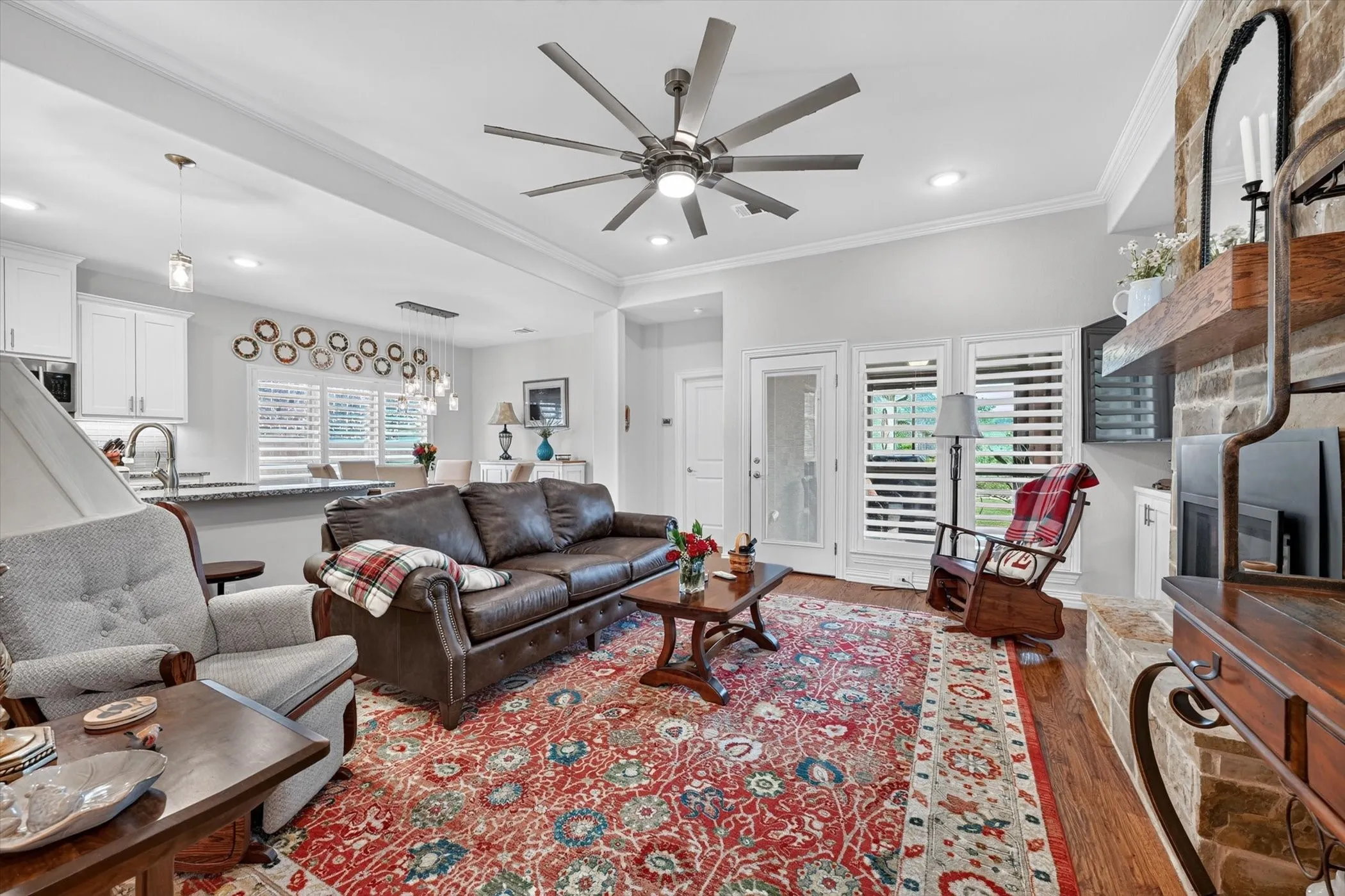Open-concept living area featuring hardwood flooring and a stone-faced fireplace with a substantial wood mantel