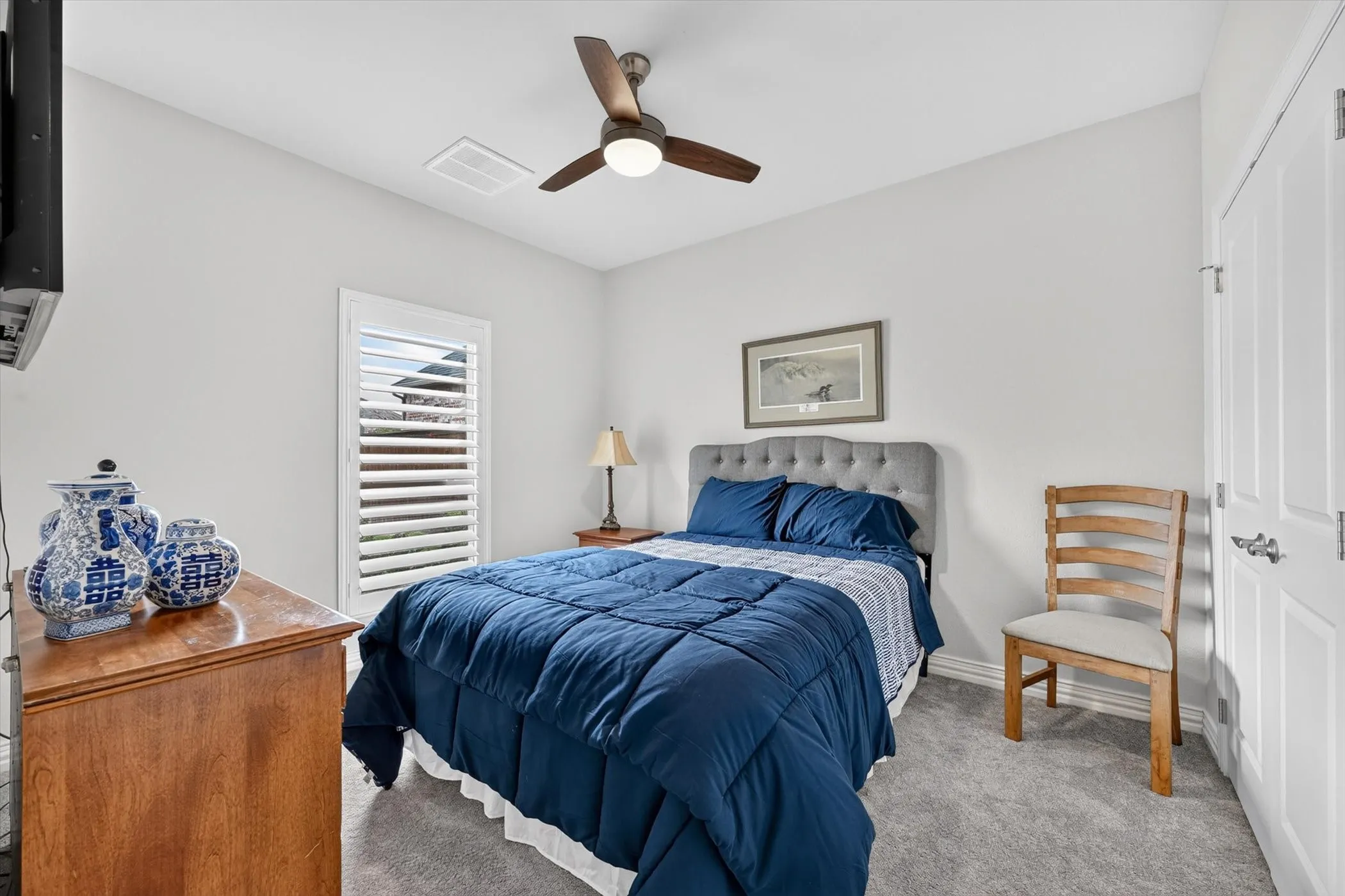 Carpeted room featuring a ceiling fan with integrated lighting, a window with plantation shutters, and a white paneled door