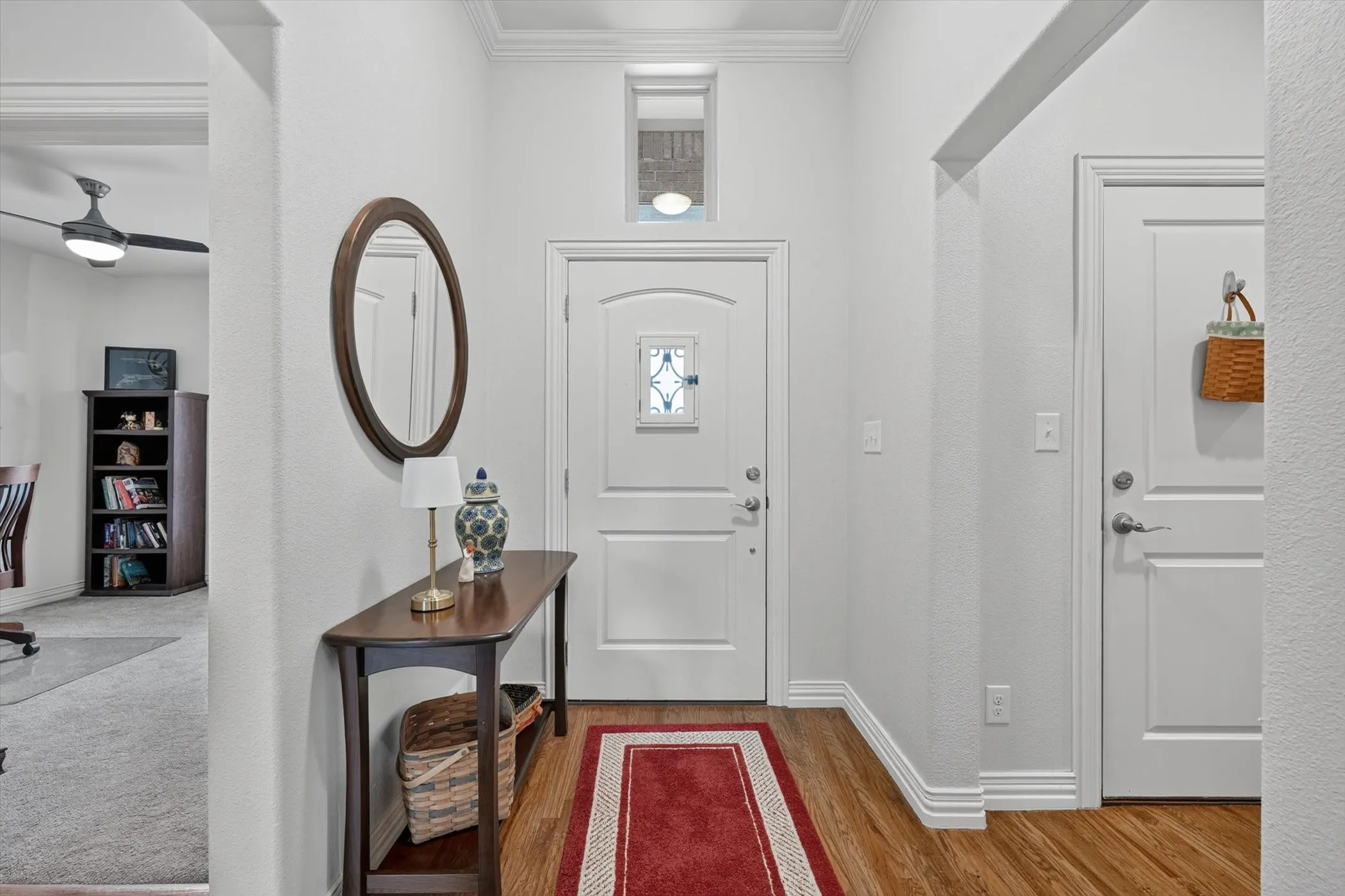 Entryway featuring wood-finish flooring, white panel doors, and crown molding