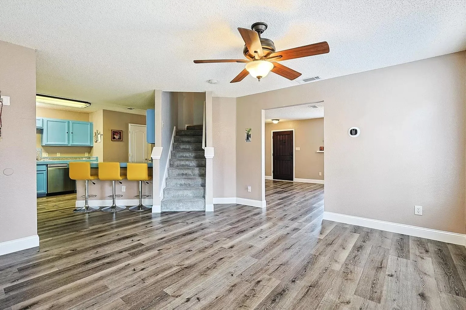 Open concept living area featuring wood-finish flooring, a ceiling fan with integrated lighting, and neutral wall tones