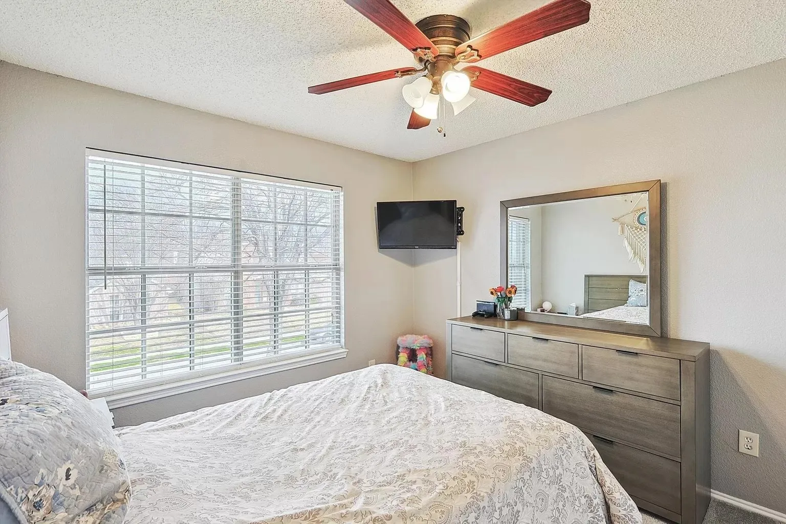 Spacious room featuring a multi-pane window with horizontal blinds, a ceiling fan with light fixture, and neutral wall tones