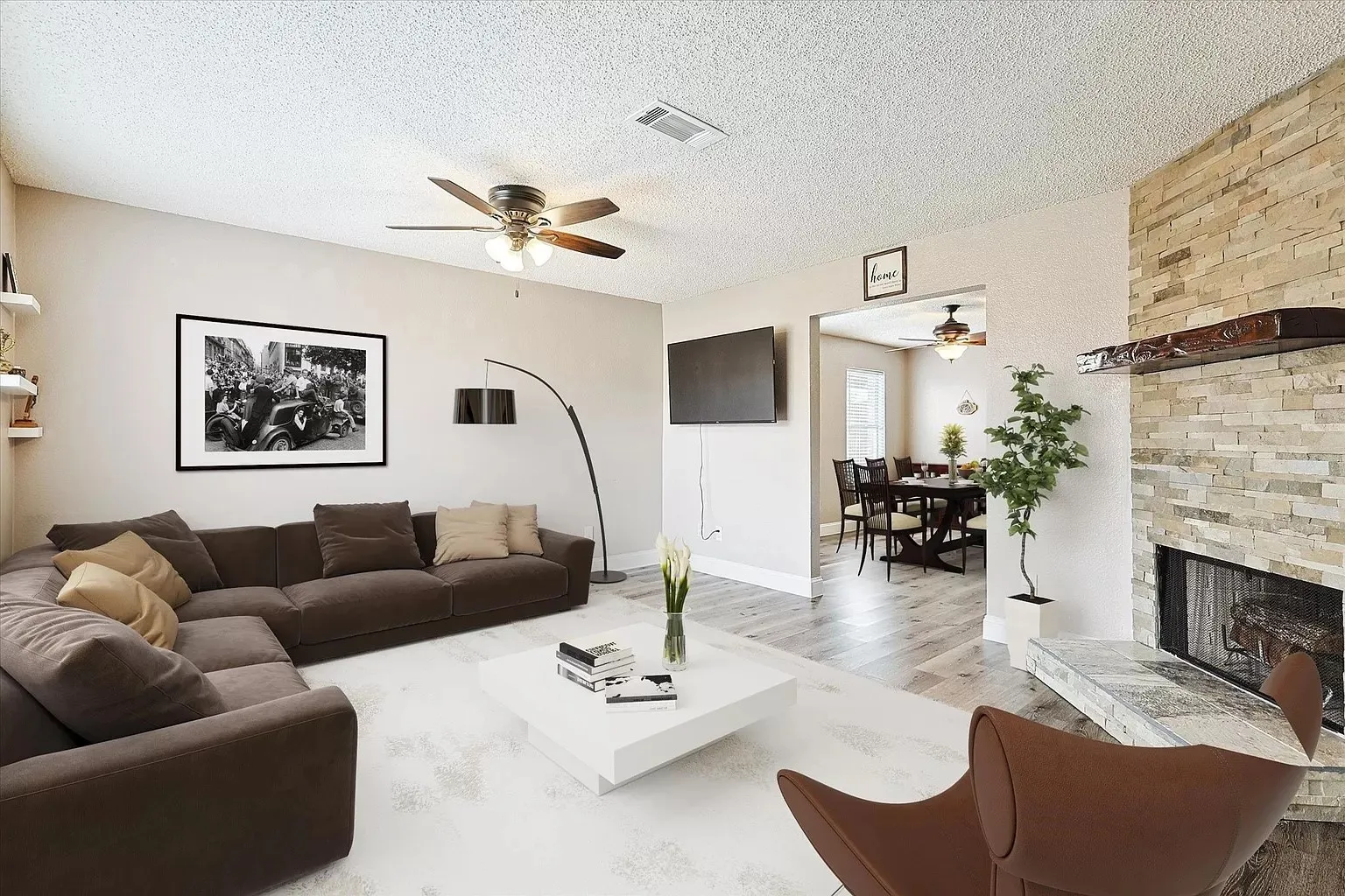 Living room featuring a stacked stone fireplace with a wood mantle, ceiling fan, and light-toned walls