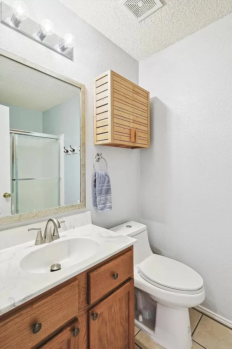 Bathroom featuring a wood-finish vanity with a single basin sink and a stone-look countertop