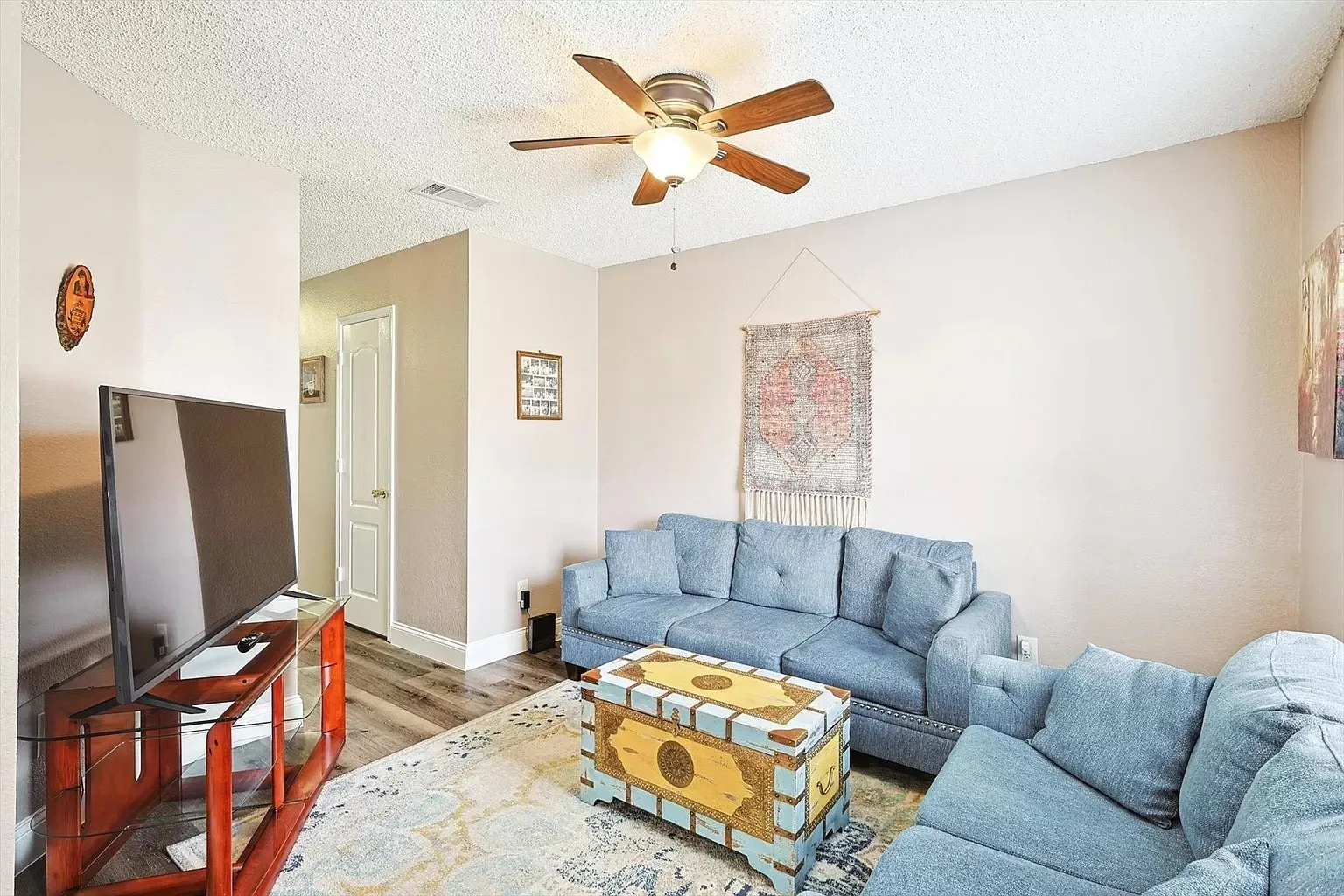 Living area featuring wood-finish flooring, a ceiling fan with integrated lighting, and neutral wall tones