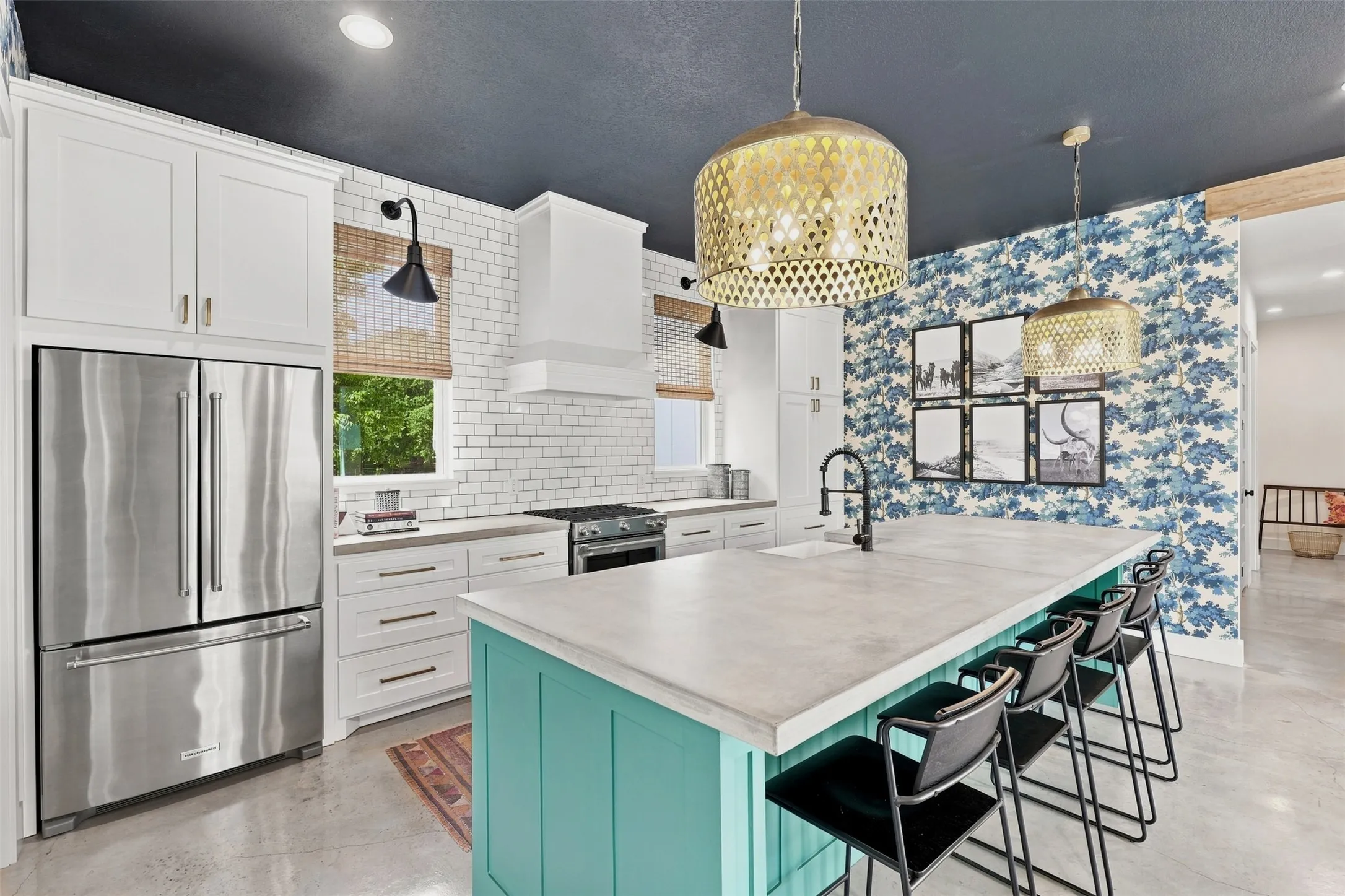 Open and naturally lit kitchen offers concrete countertops, farm style sink, subway tile and gas range.