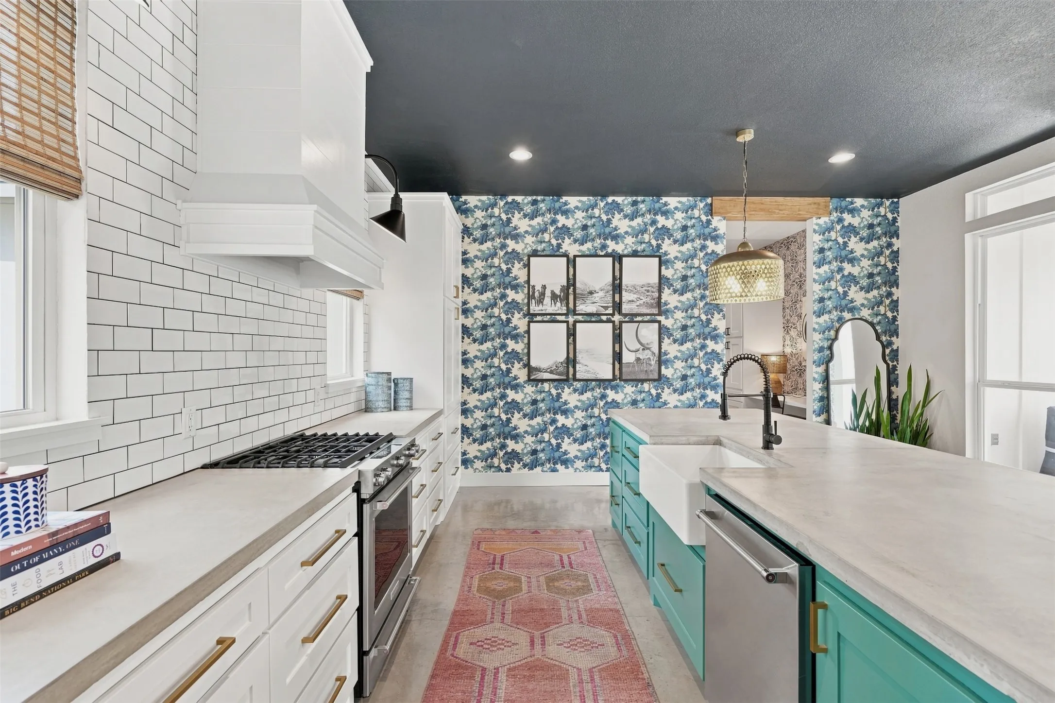 Open and naturally lit kitchen offers concrete countertops, farm style sink, subway tile and gas range.