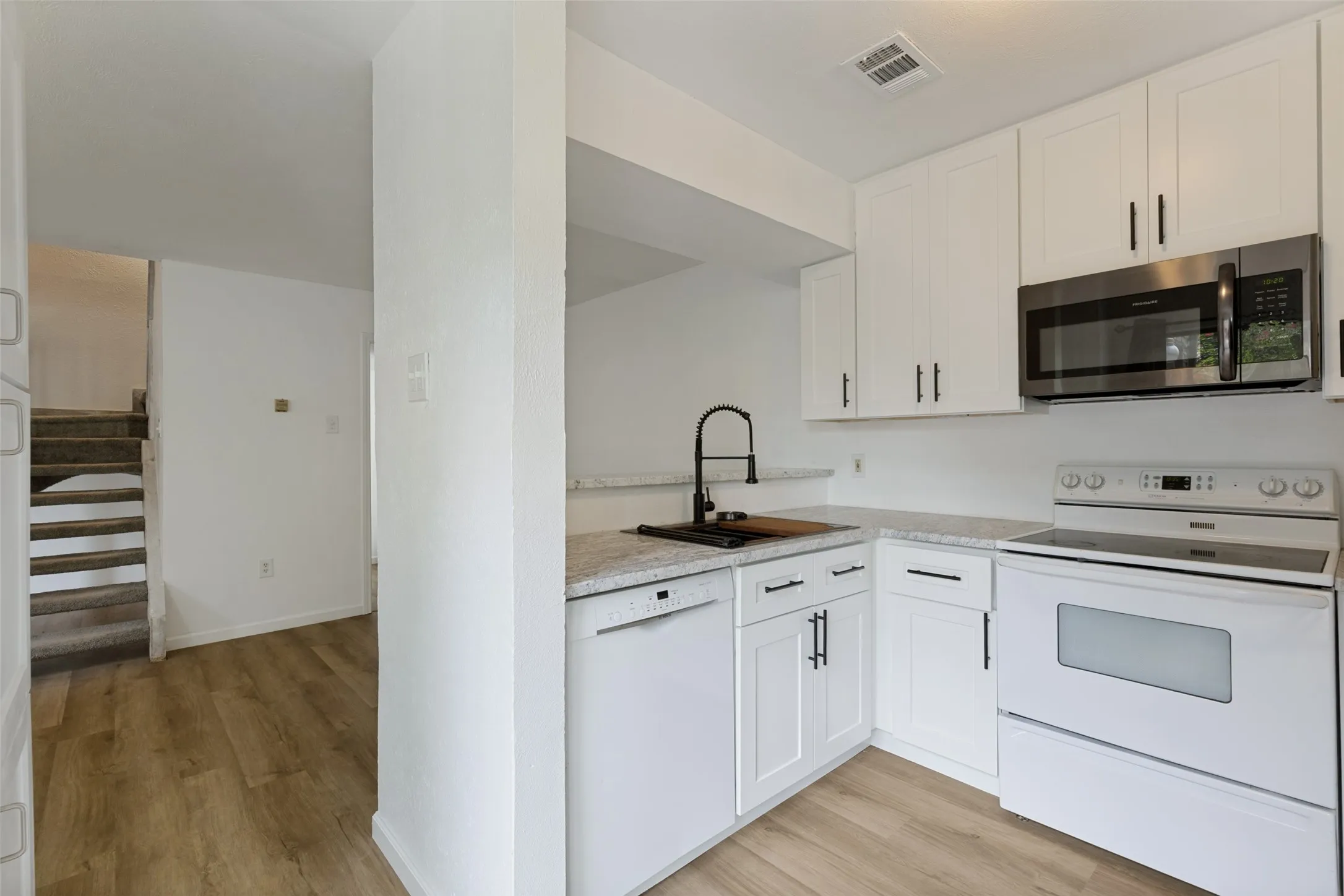 Kitchen featuring white shaker-style cabinetry, a stainless steel microwave, white range, and a dishwasher