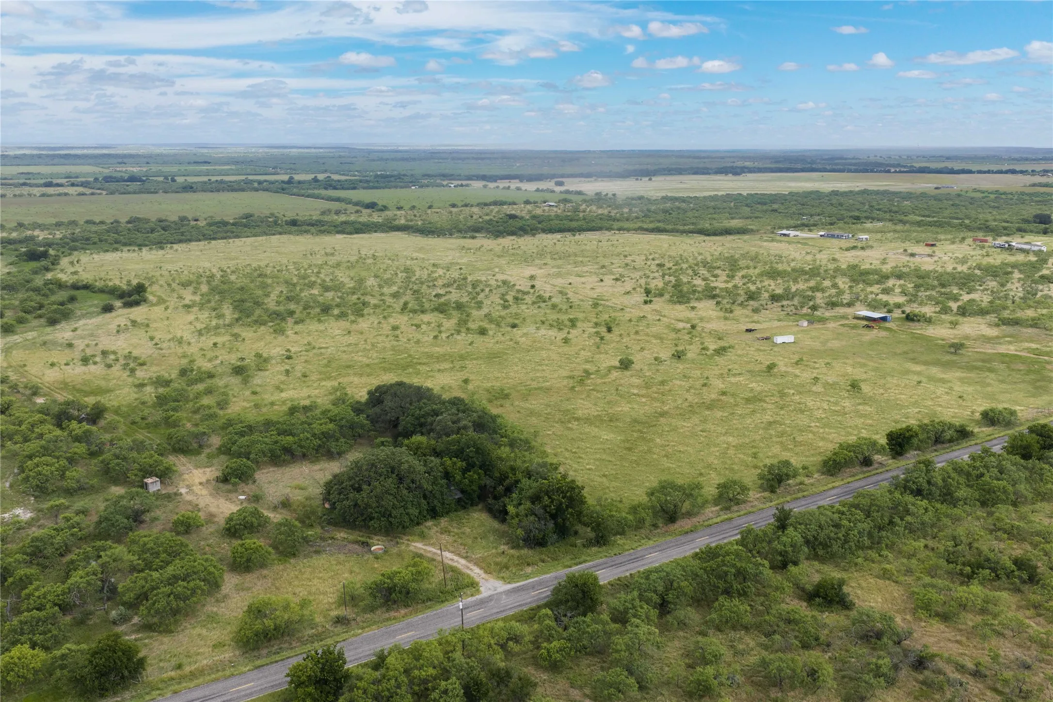 Expansive open land featuring diverse vegetation and scattered trees