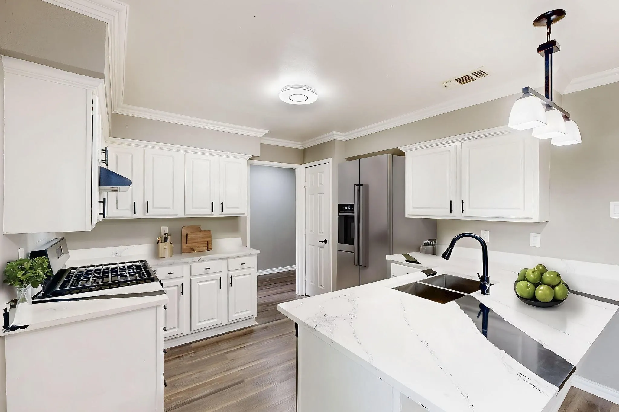 *Virtually staged*
Kitchen featuring a sink, light wood-style floors, white cabinetry, and crown molding