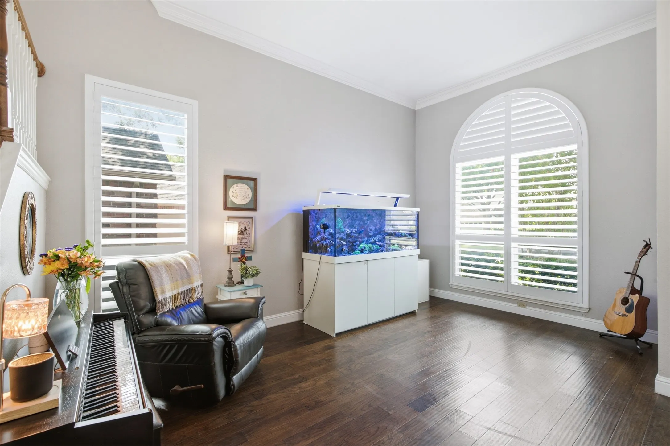 Hardwood flooring throughout featuring a large arched window with plantation shutters