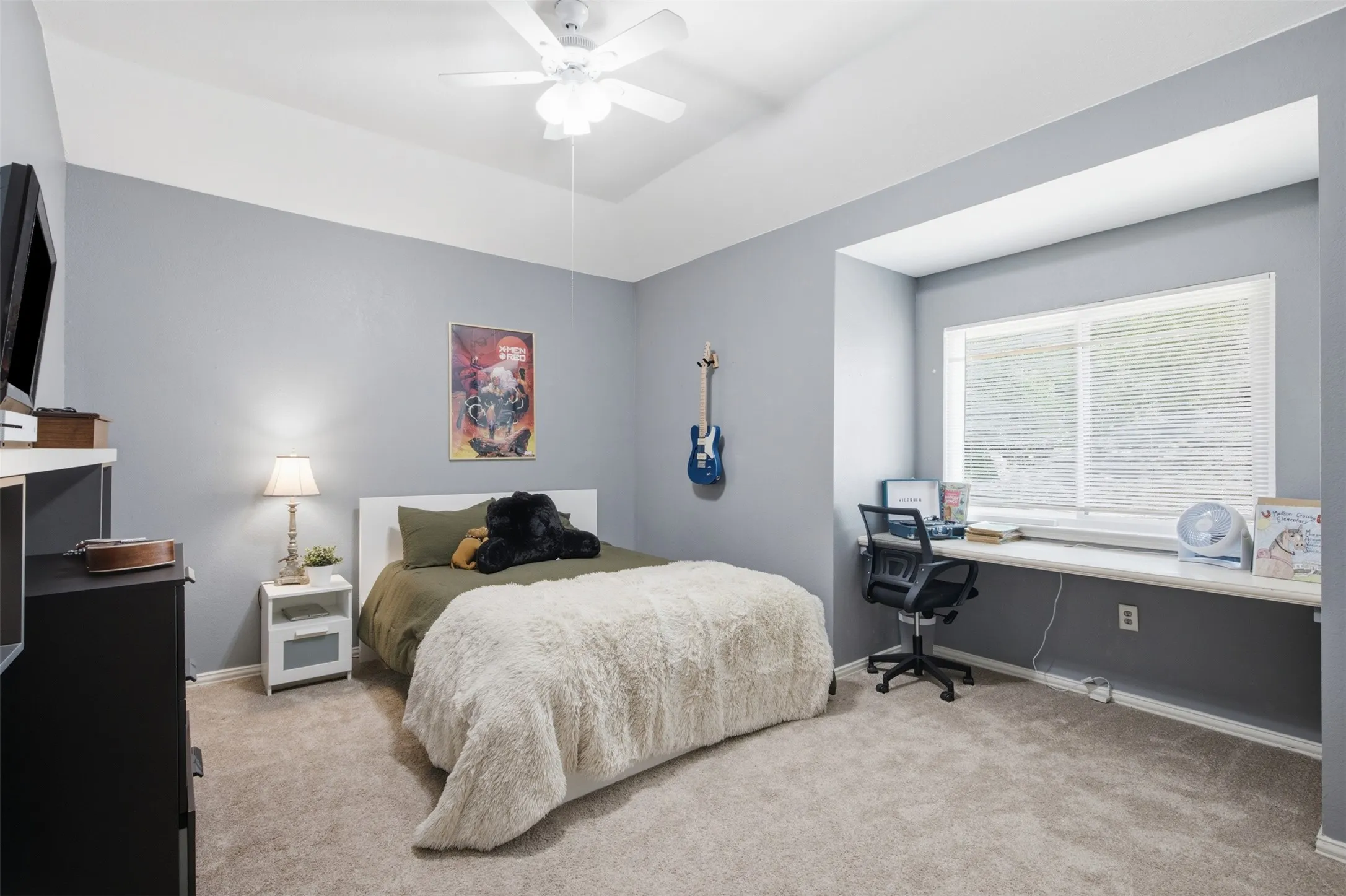 Carpeted room featuring a ceiling fan, recessed window alcove, and a built-in desk with a window