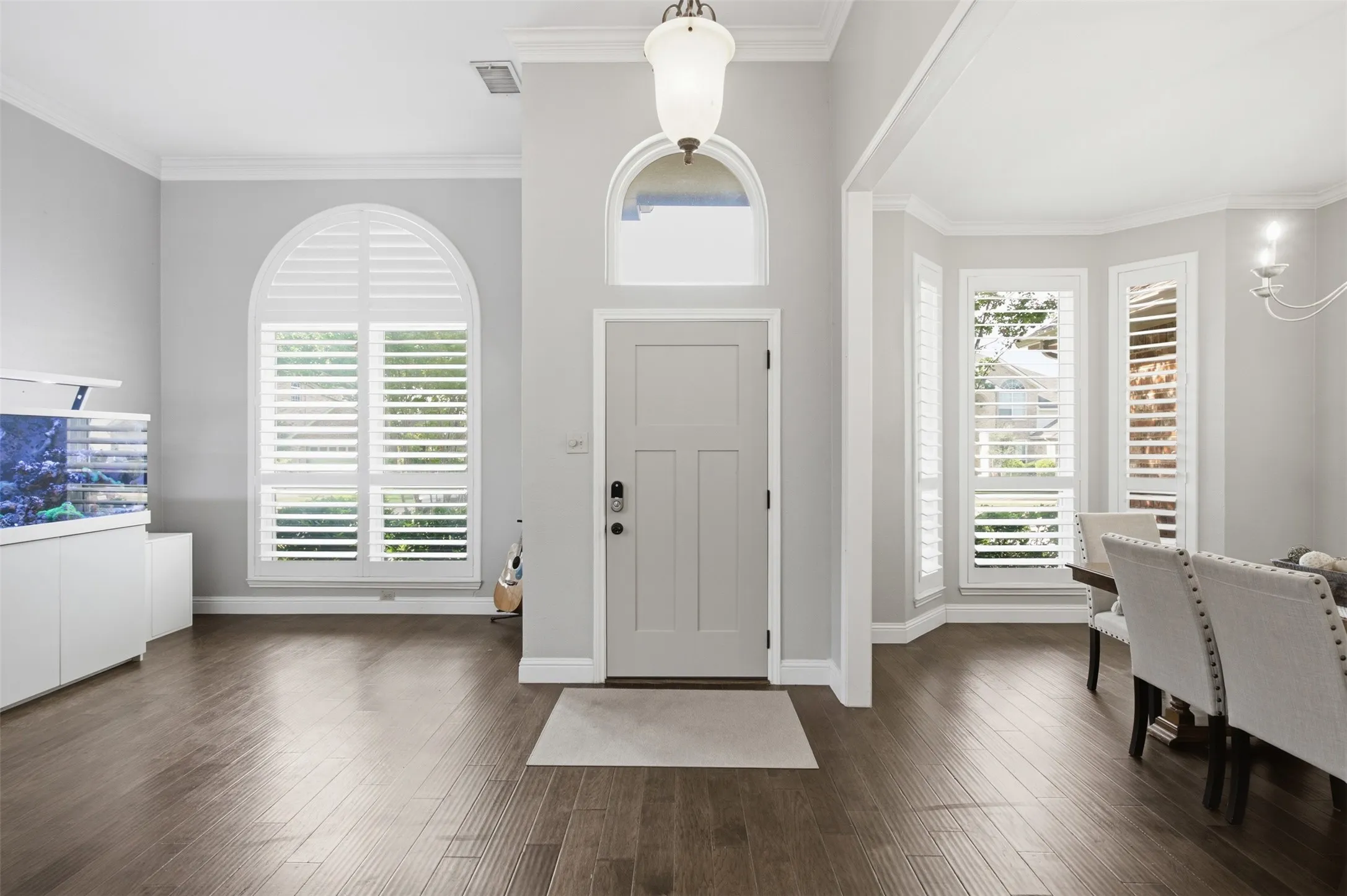 Entryway featuring a panel door with an arched transom window, wood-finish flooring, and crown molding