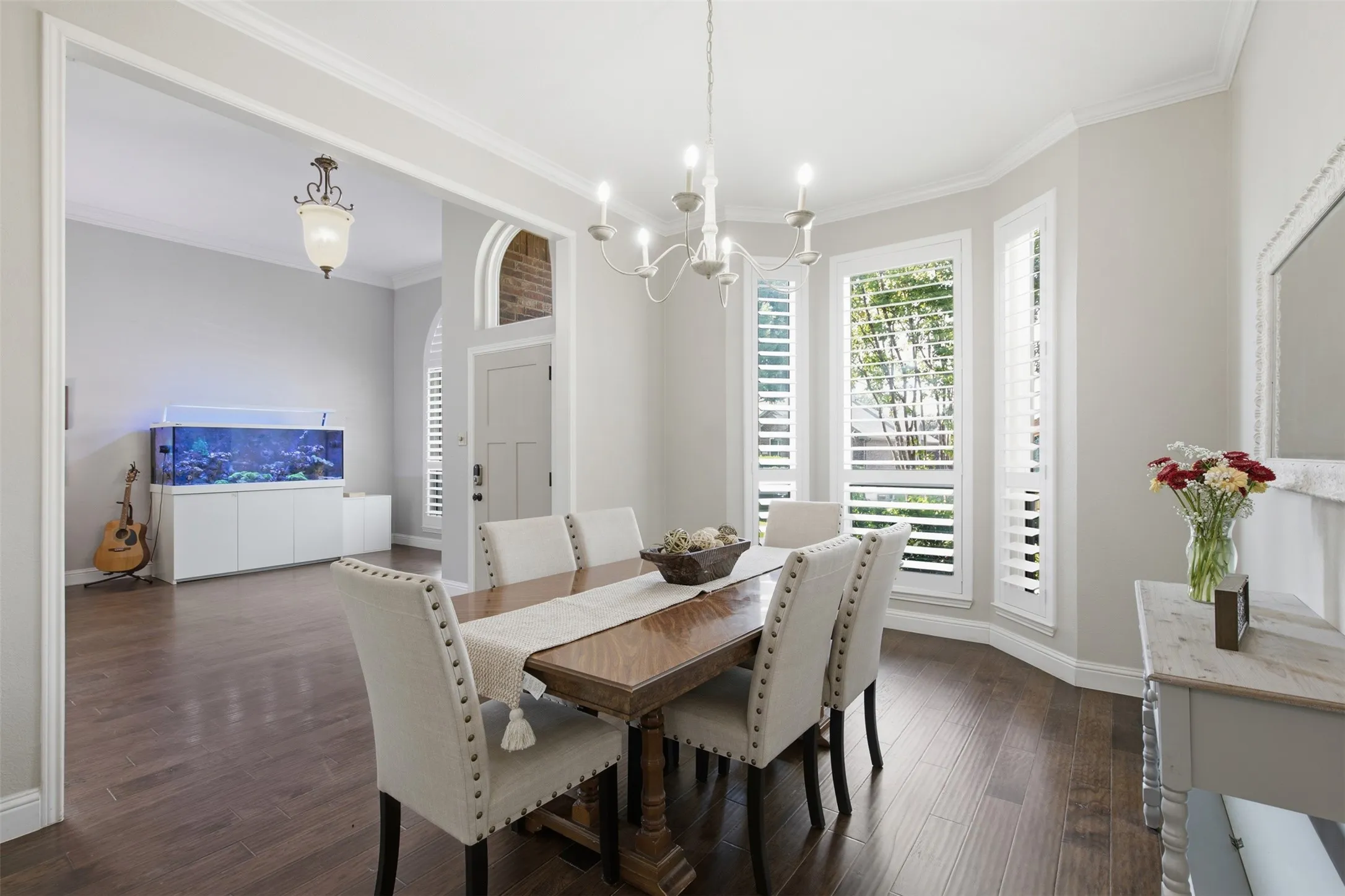 Dining area featuring dark wood-finish flooring, light gray wall paint, and white crown molding
