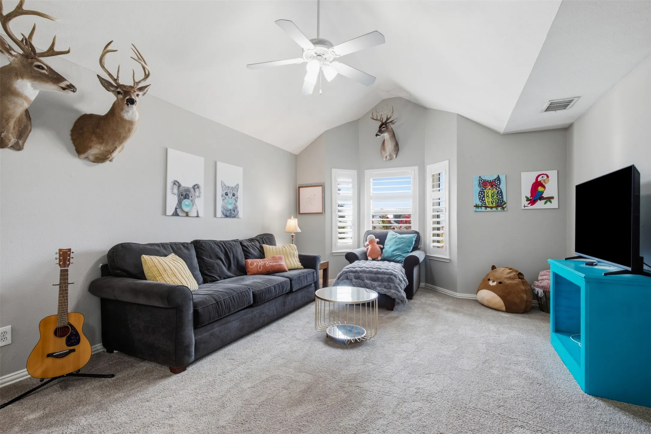 Carpeted room featuring a vaulted ceiling with a ceiling fan