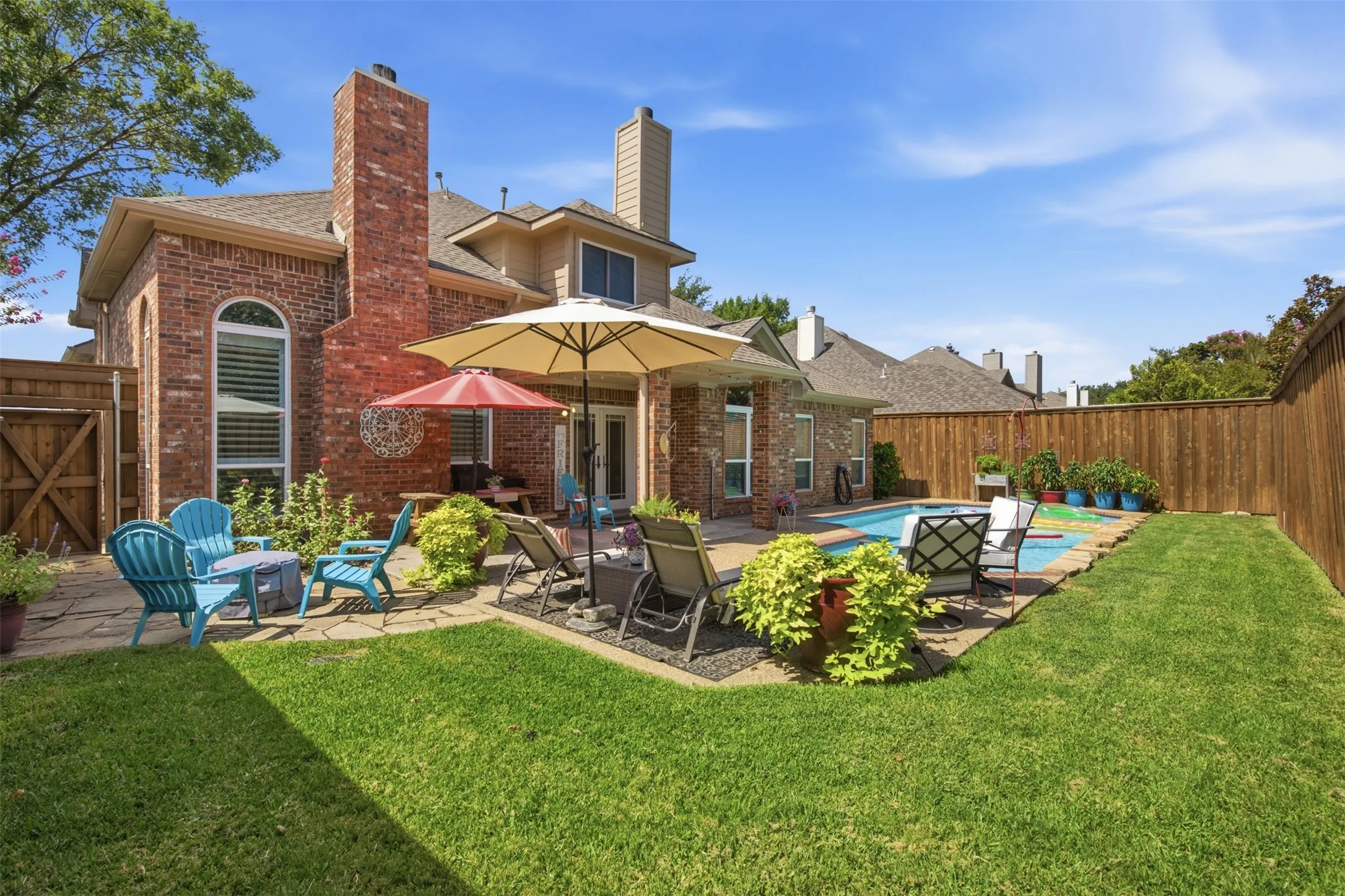 Expansive backyard featuring a rectangular swimming pool, a stone patio, and a wood privacy fence
