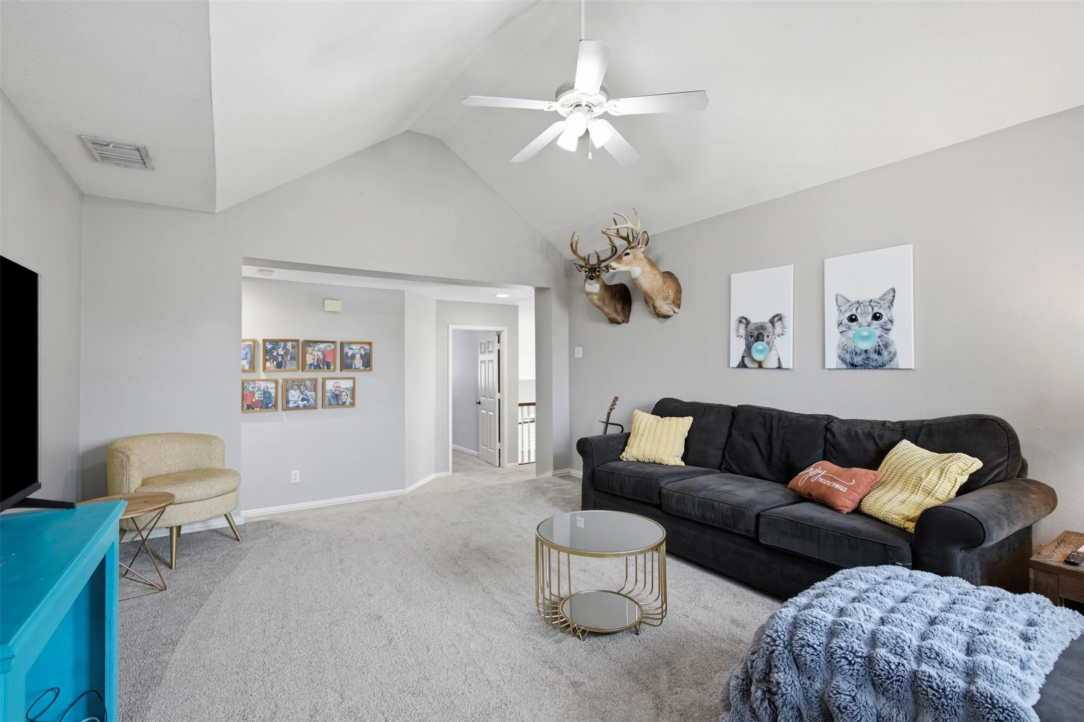 Carpeted living area featuring a vaulted ceiling and a ceiling fan with integrated lighting