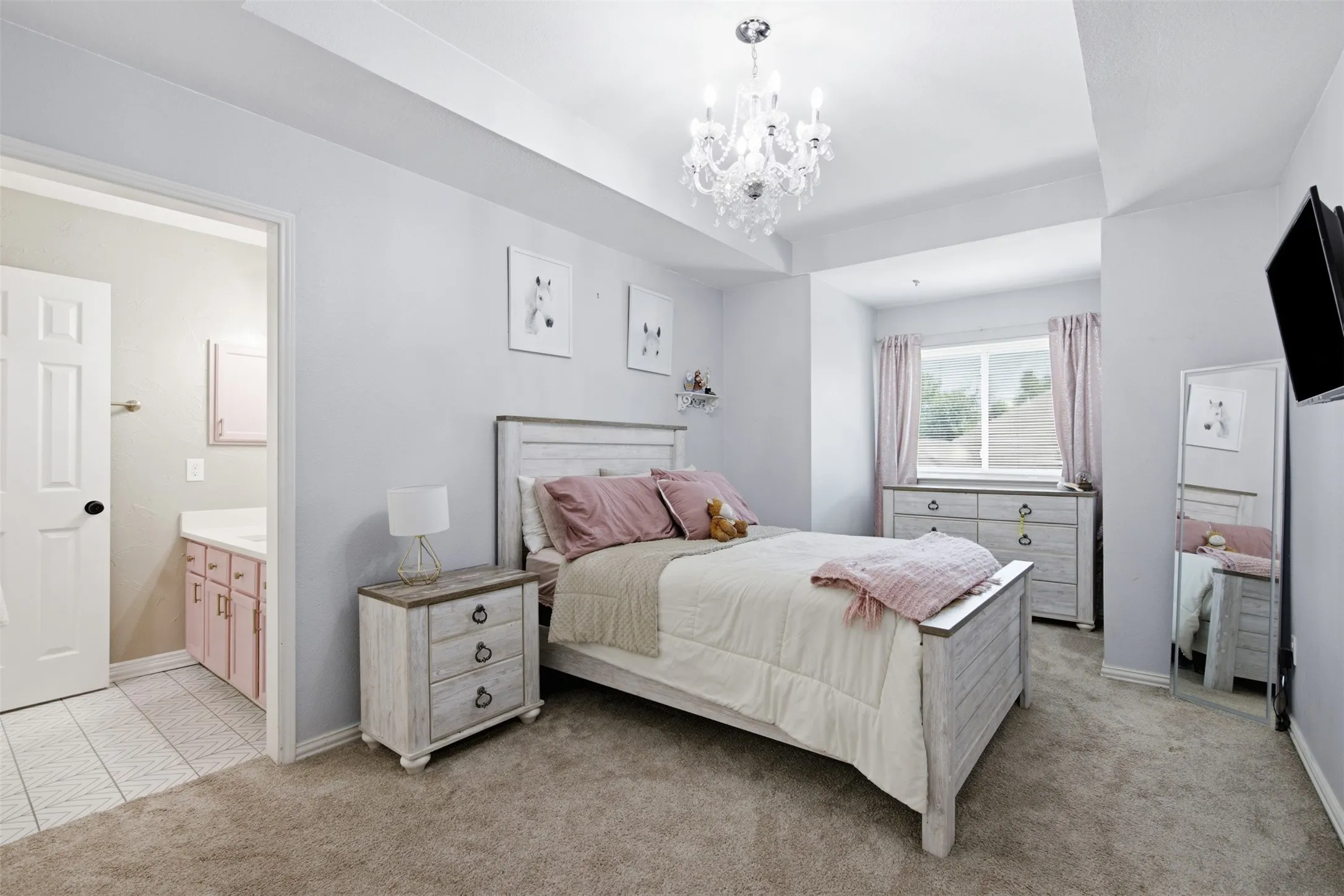 Carpeted bedroom featuring a crystal chandelier and a window with neutral drapes