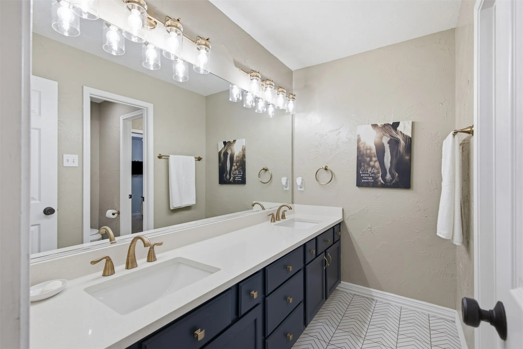 Double vanity with white undermount sinks and bronze-finish faucets