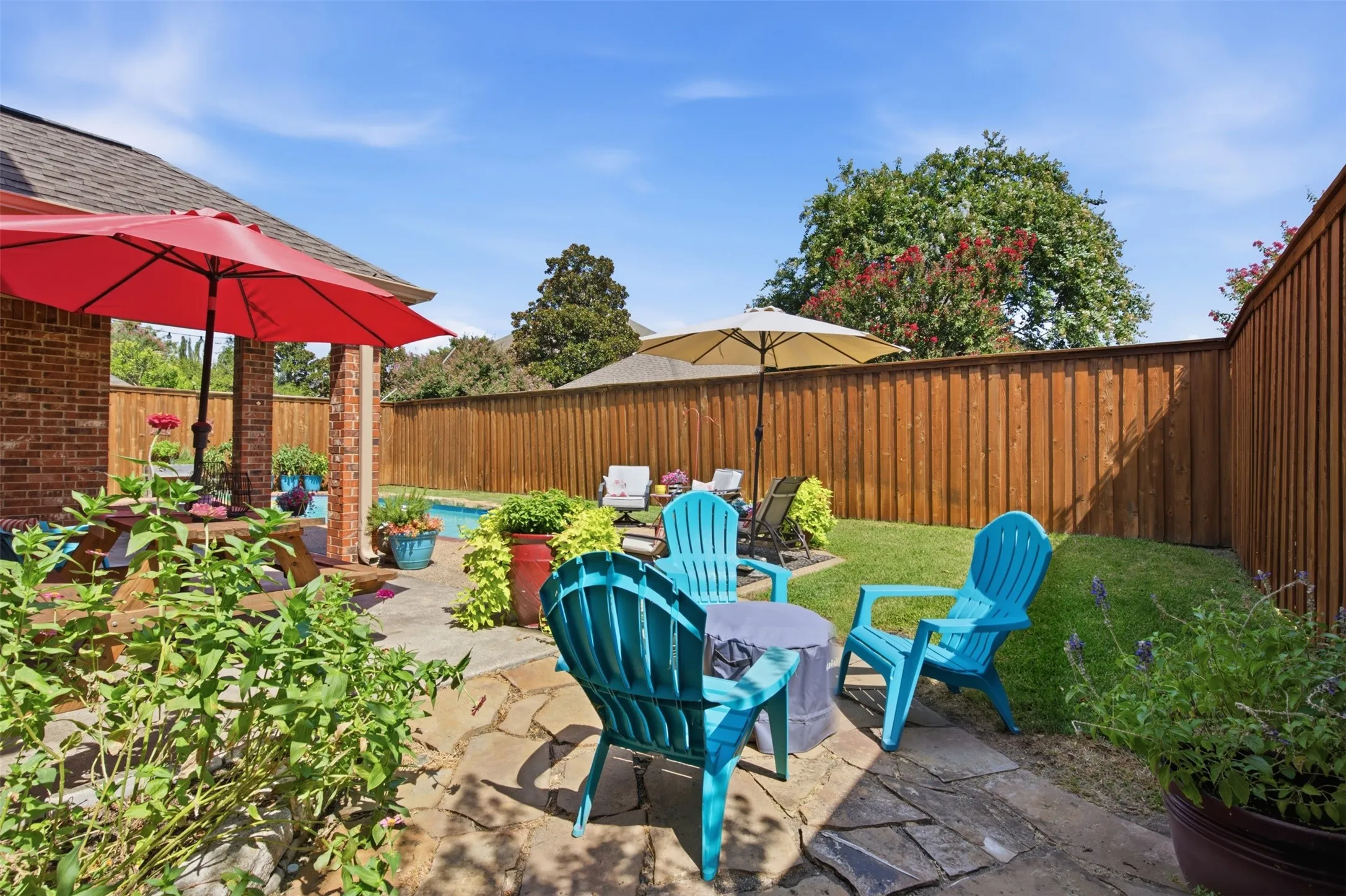 Outdoor living area featuring a flagstone patio, manicured lawn, and a privacy fence