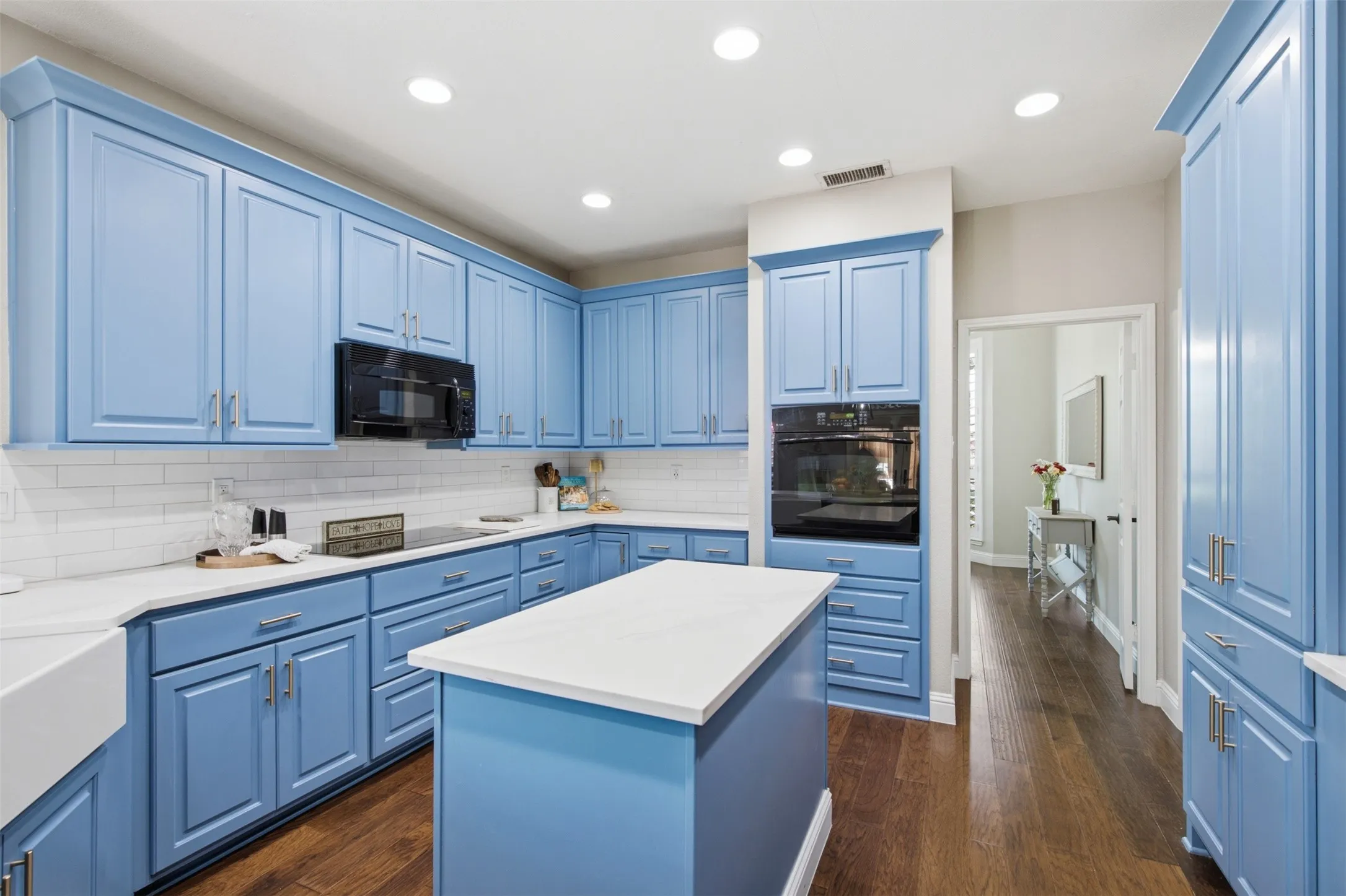 Kitchen featuring blue cabinetry, white countertops, built-in oven, integrated microwave, and wood-finish flooring