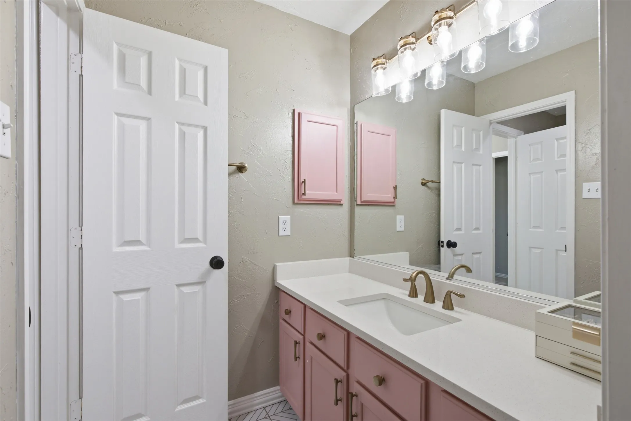 Vanity with white countertop, recessed sink, and brass-finish faucet