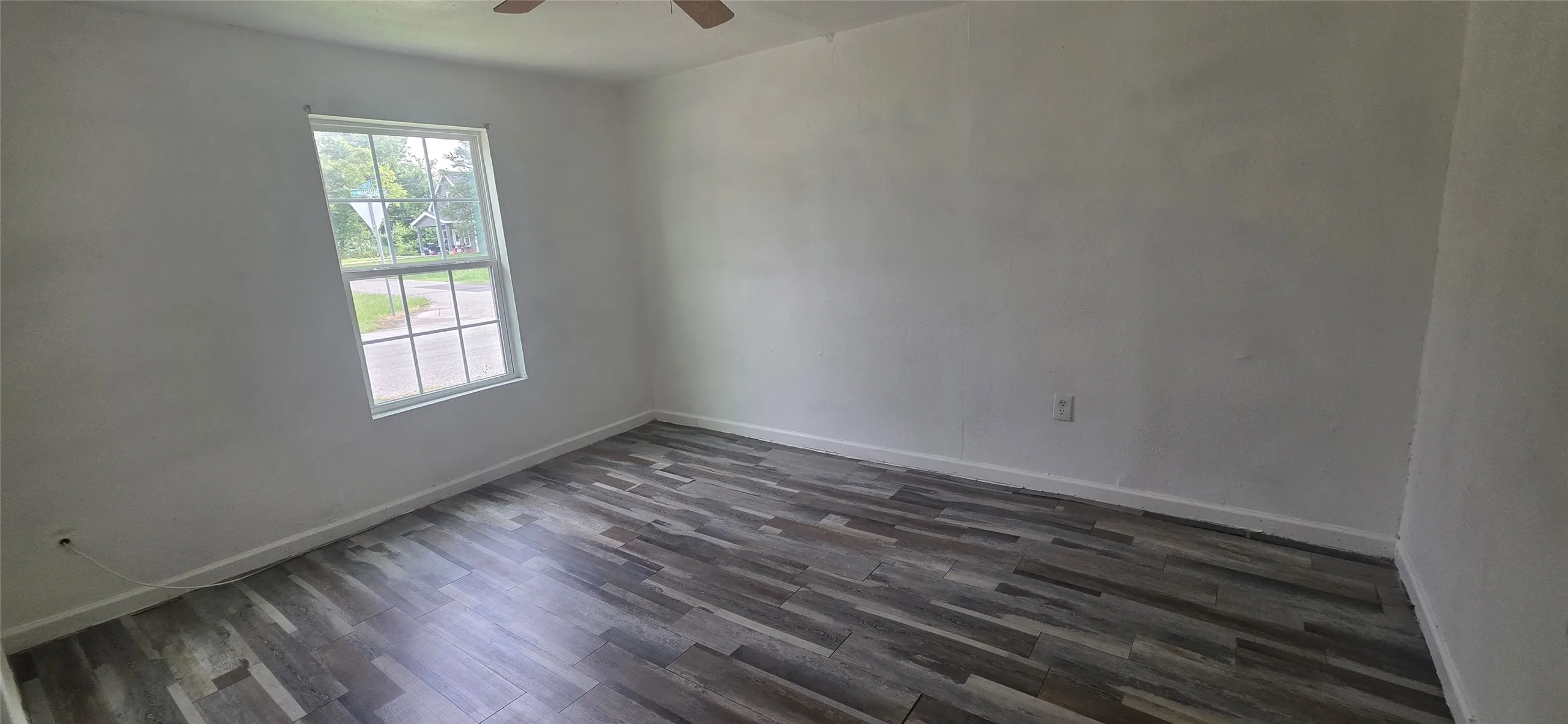Room featuring wood-finish flooring, white walls, and a multi-pane window