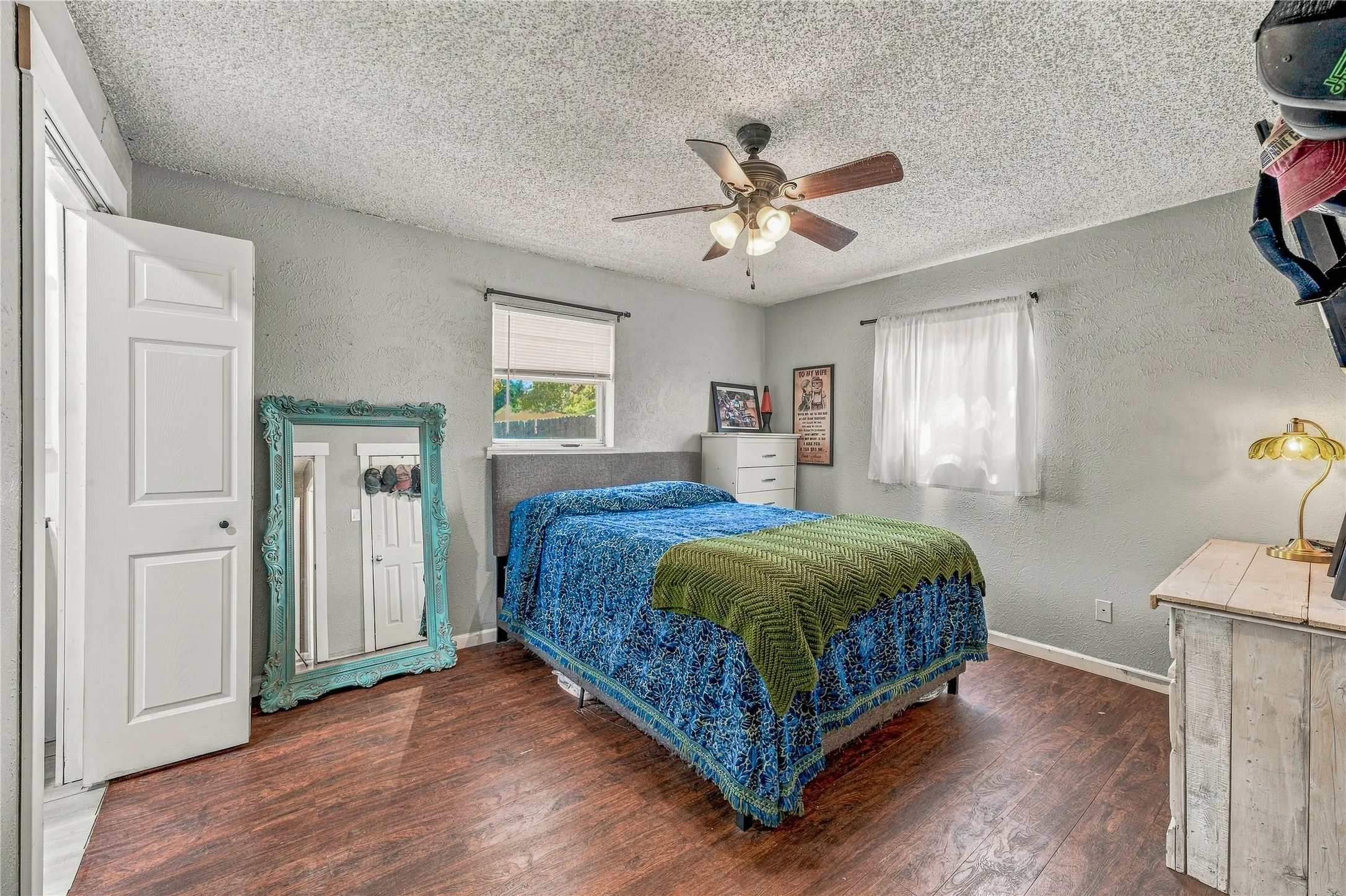 Wood-finish flooring, textured walls, and a ceiling fan with integrated lighting