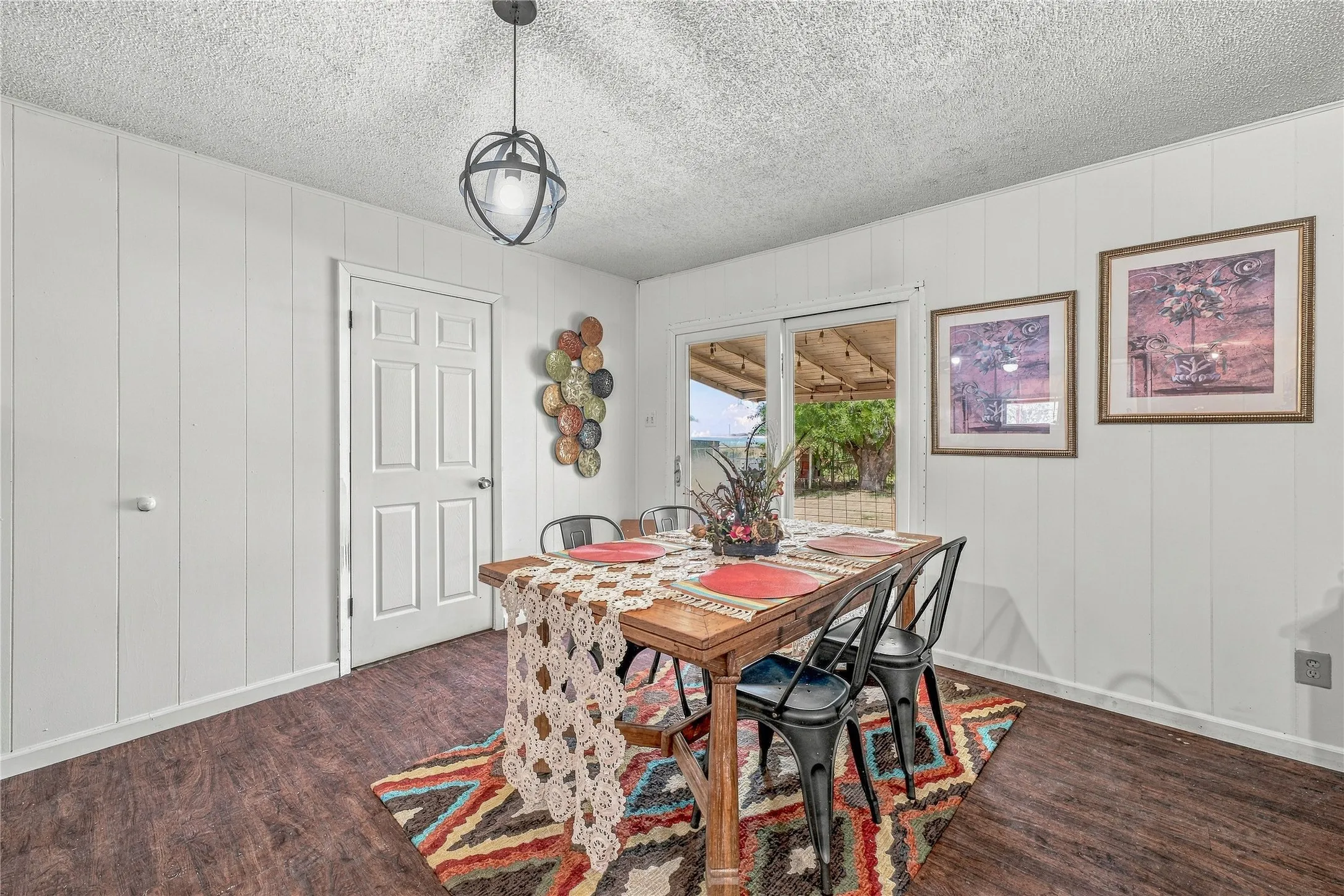 Wood-finish flooring, white paneled walls, and a modern pendant light fixture