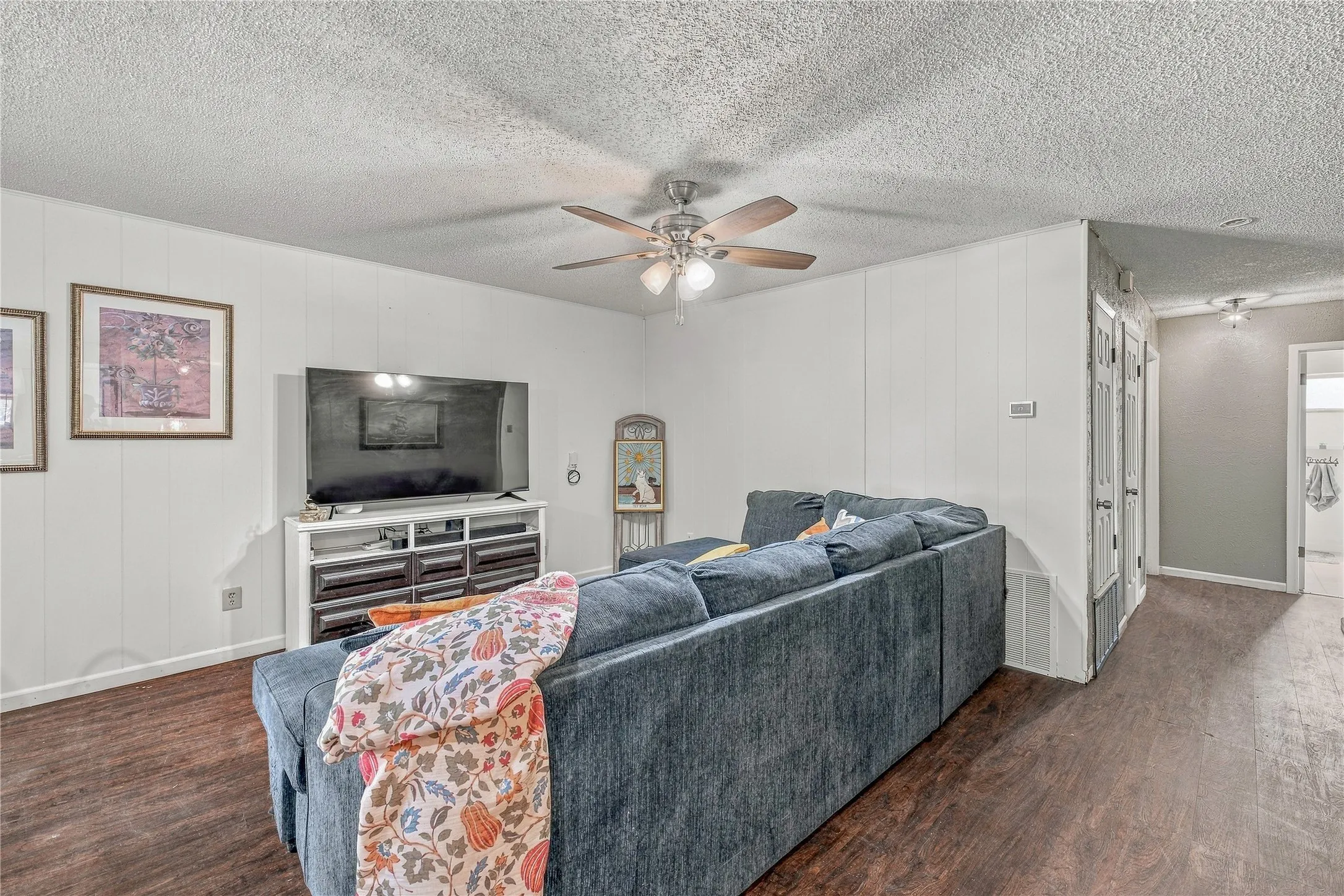 Wood-finish flooring, paneled walls, and a ceiling fan with integrated lighting