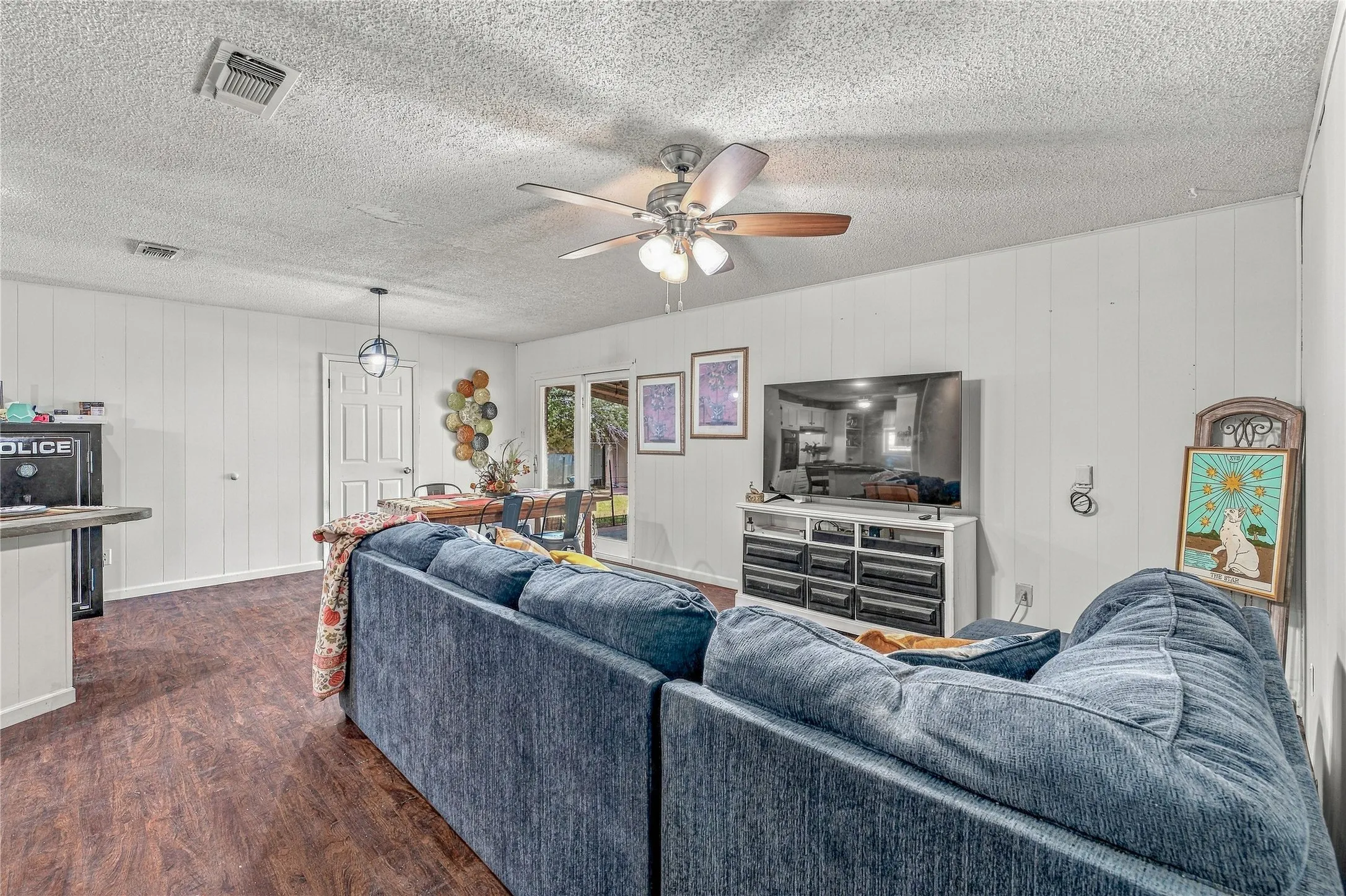 Wood-finish flooring throughout, white paneling walls, and a ceiling fan with light fixture